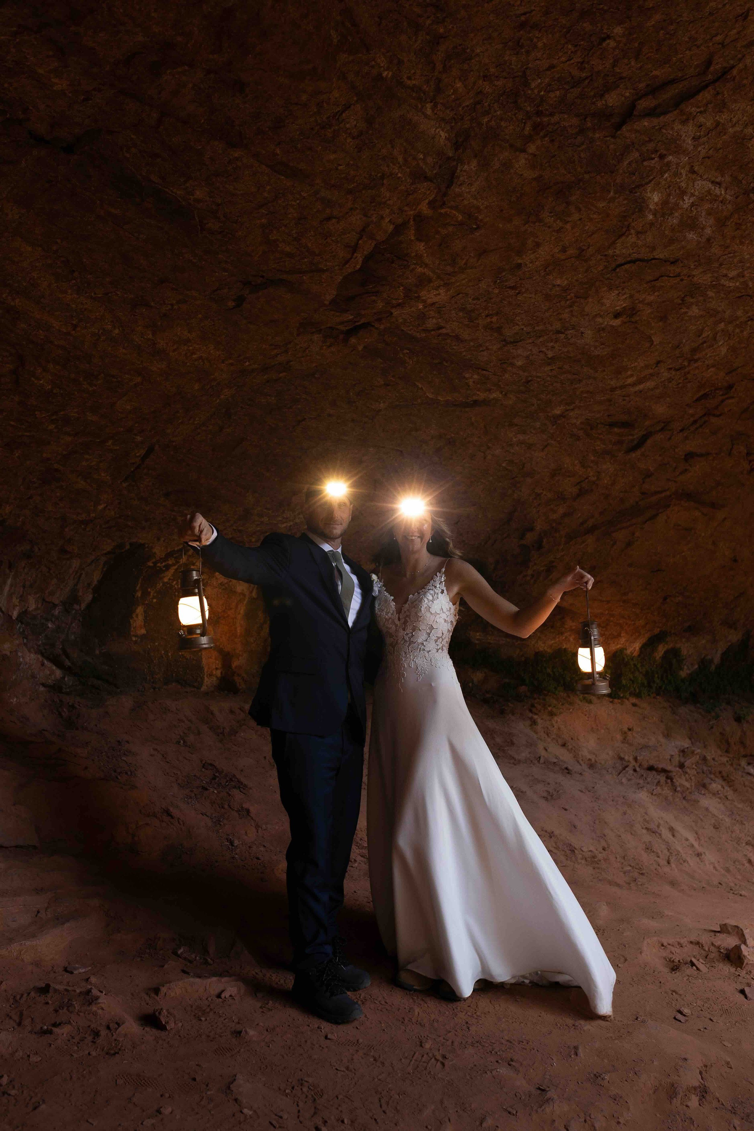 Bride and groom with lamps and headlights on their heads in a cave.