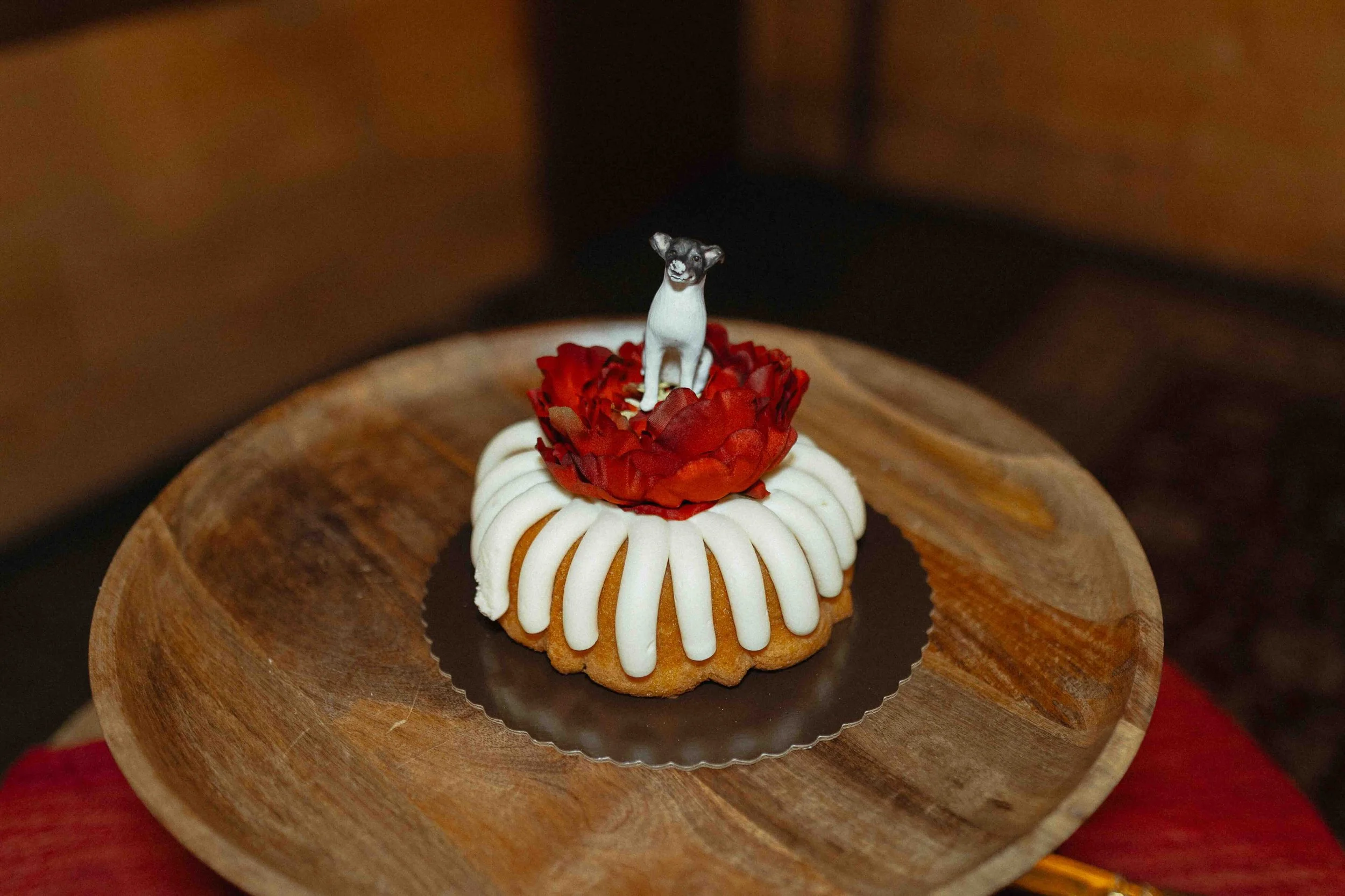 Wedding bundt cake with a red flower on top and a dog topper.