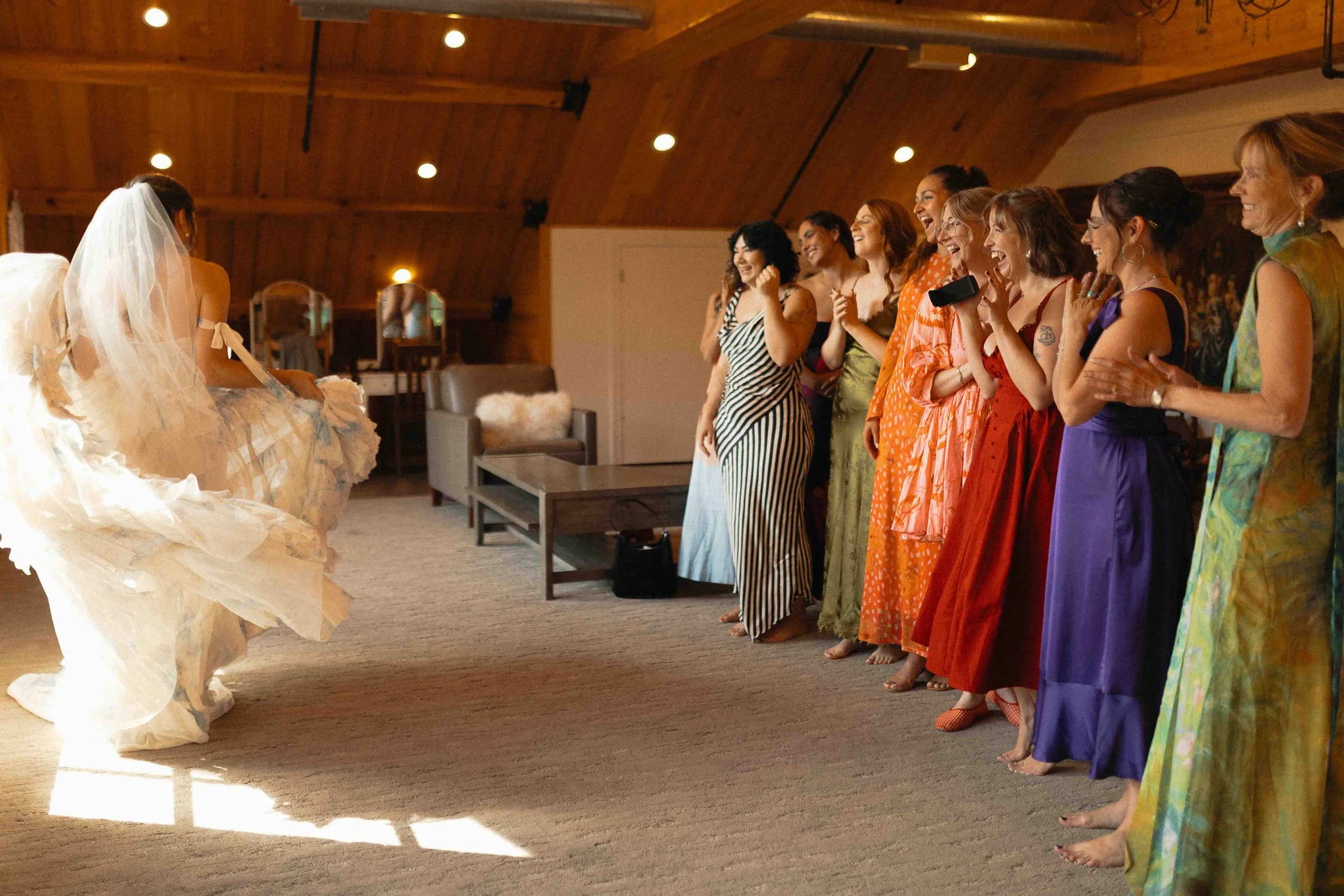 Bride twirling her dress in front of bridesmaids in all different color dresses.