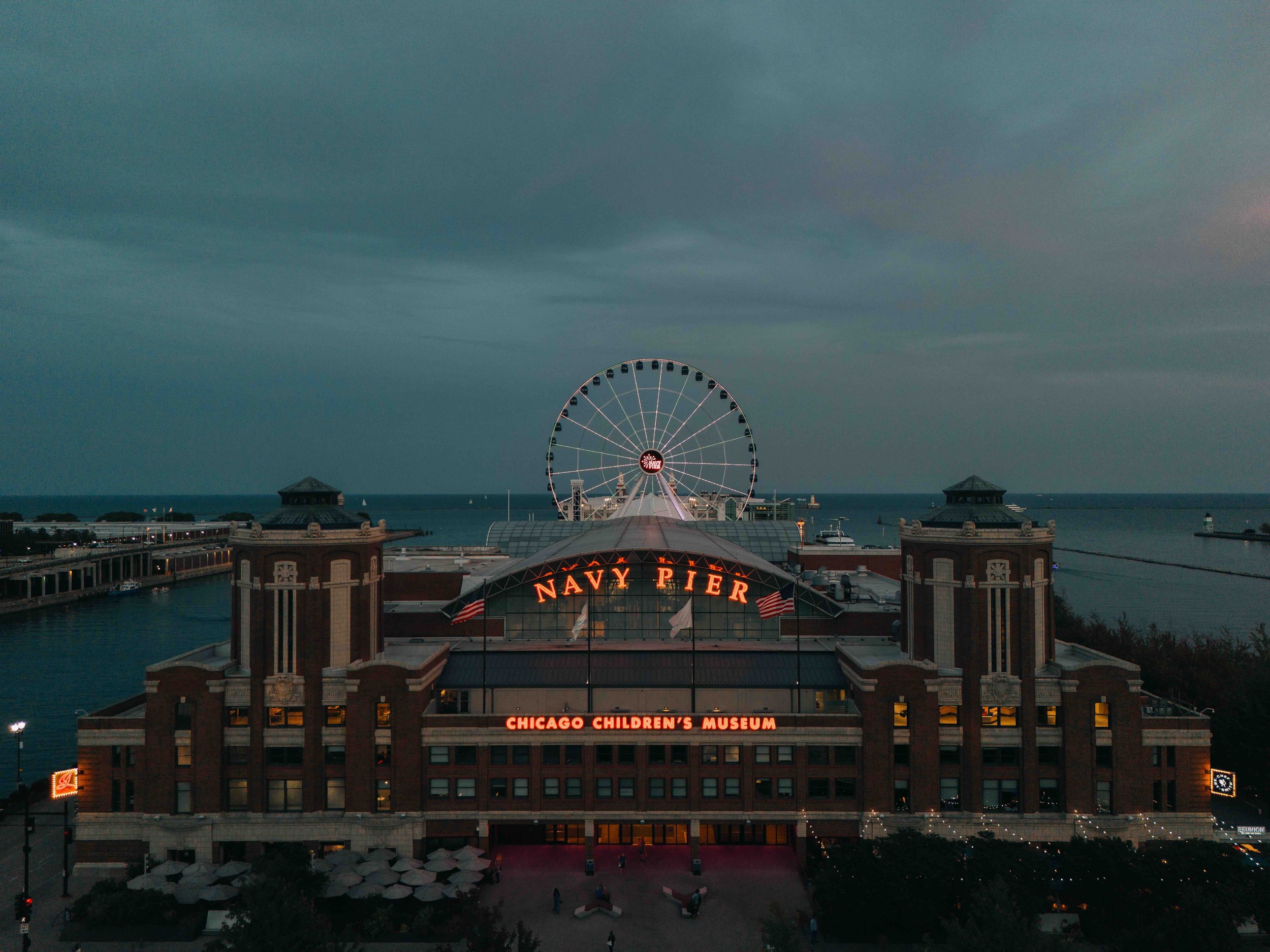 A building that stretches out on Navy Pier over Lake Michigan with a ferris wheel in the background.