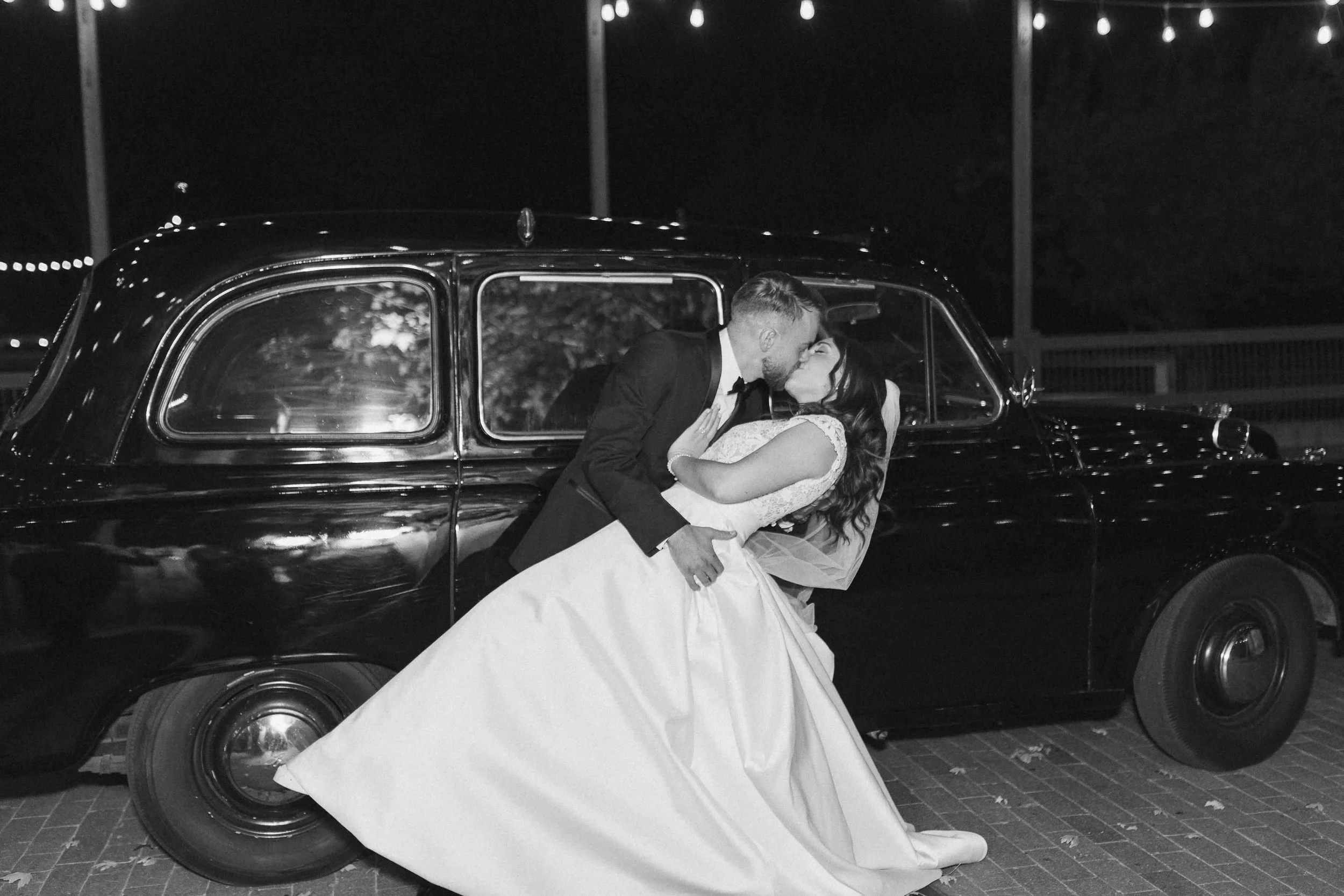 Bride and groom dipping and kissing in front of a black London Limo.
