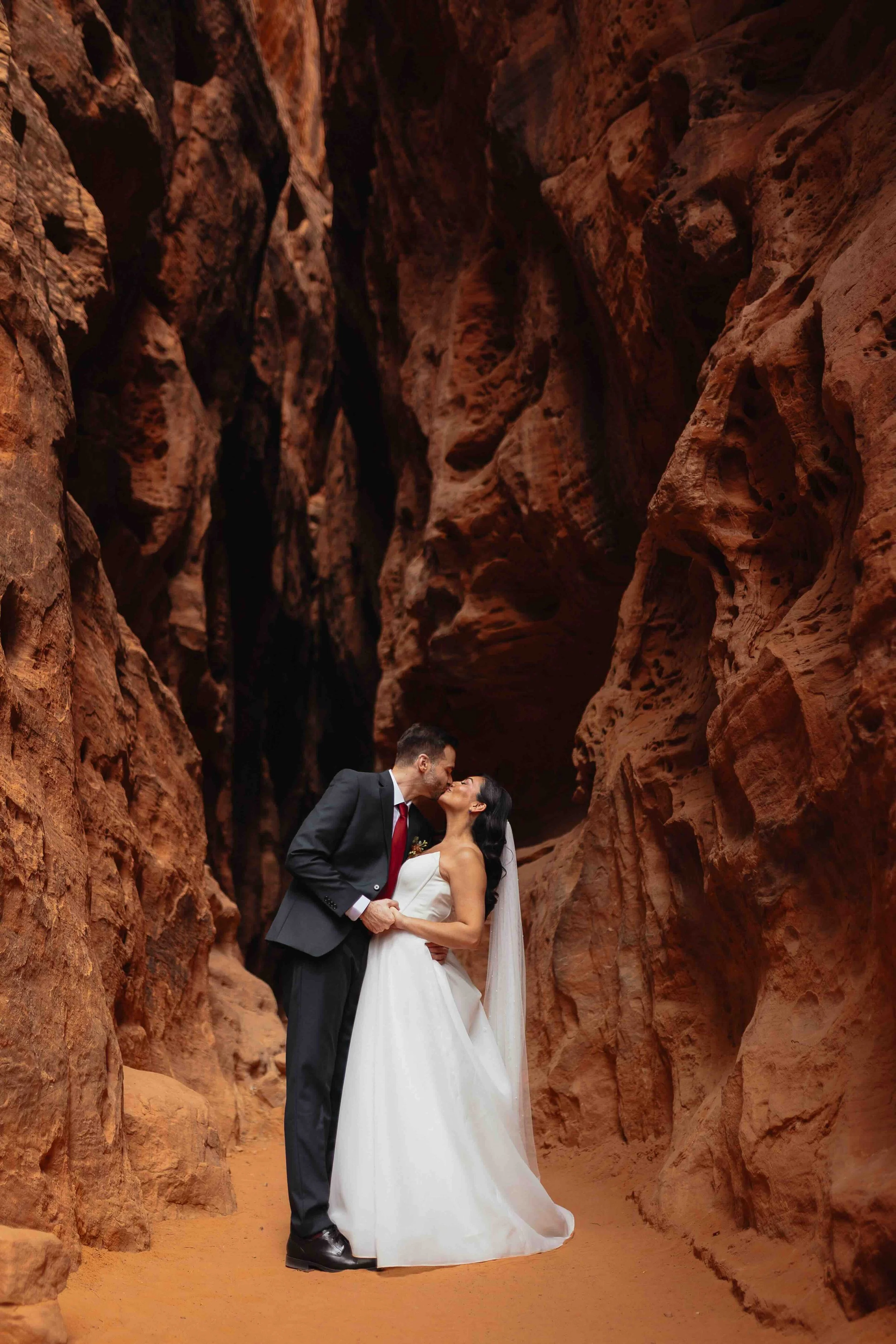 a bride and groom kissing in a slot canyon.