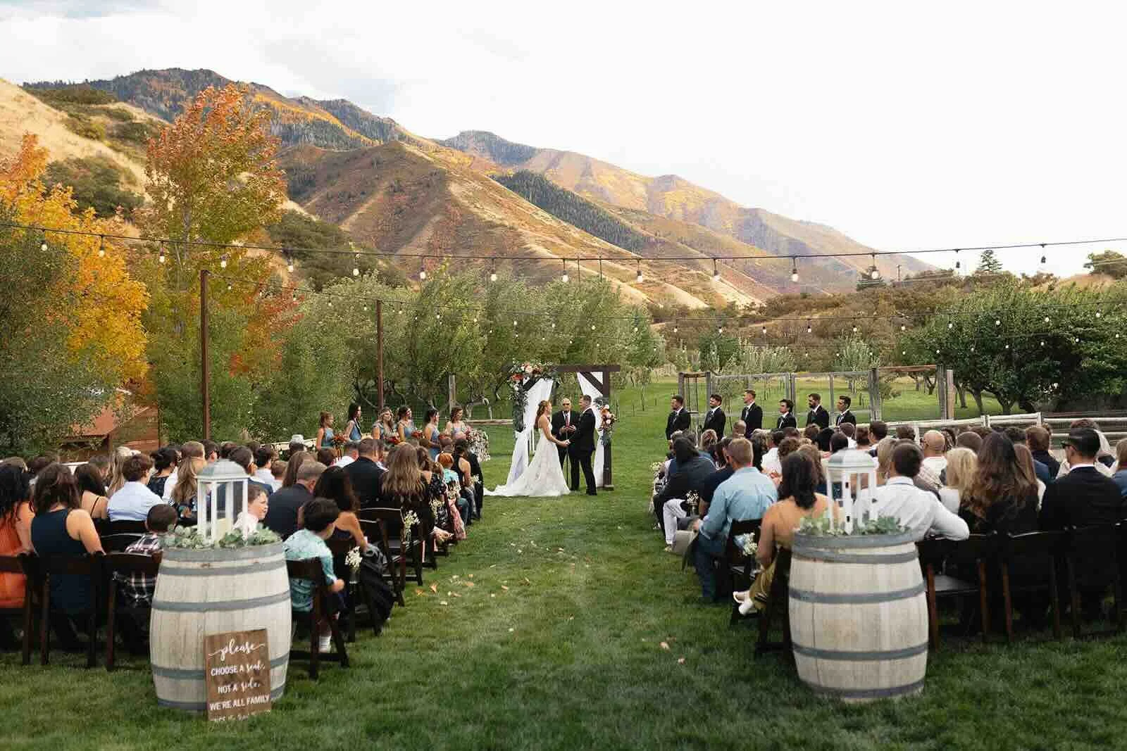 Wedding ceremony taking in place in a green field in front of a mountain view. The couple is standing at the alter. 