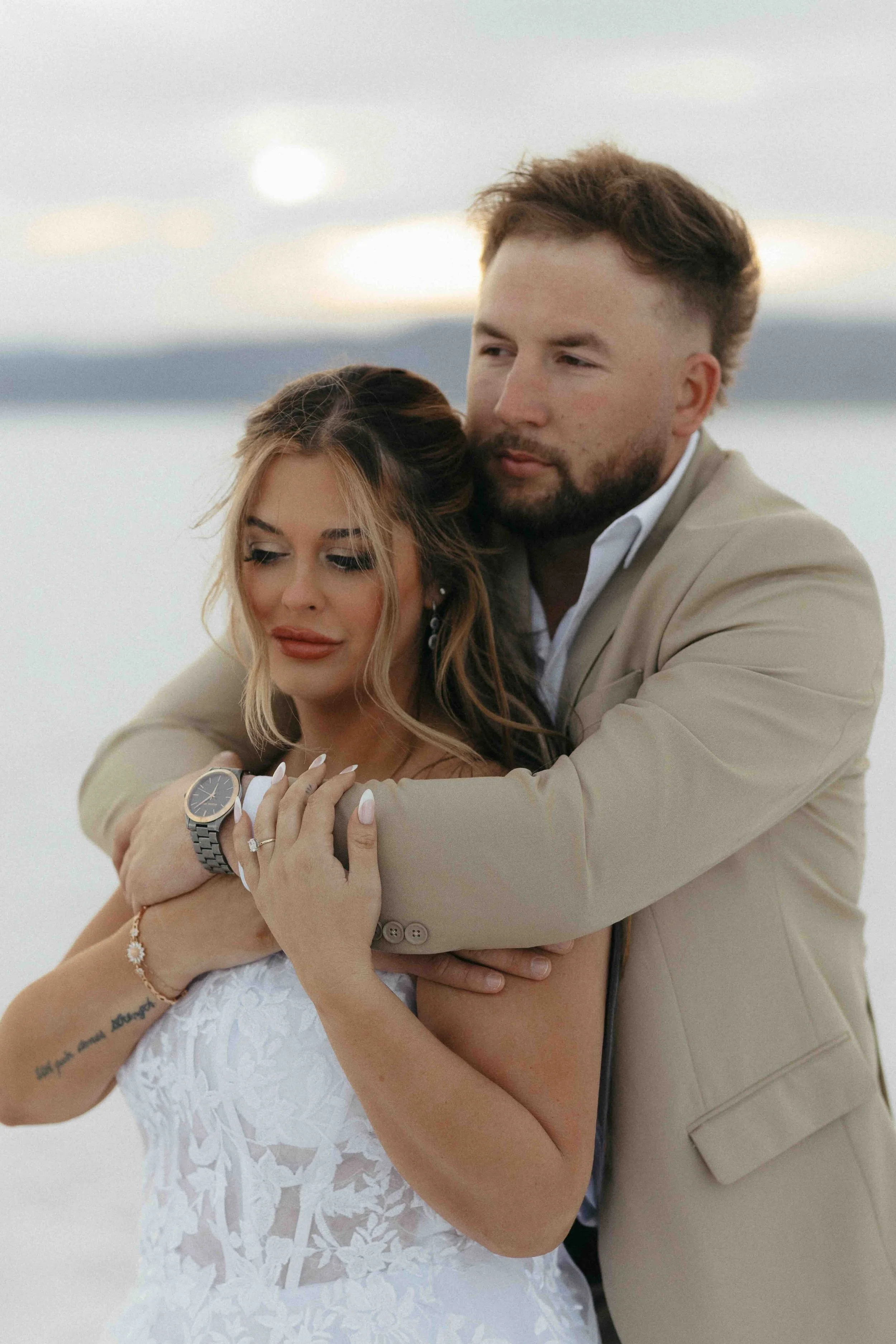 Bride and groom cuddling one another on the salt flats of Utah.