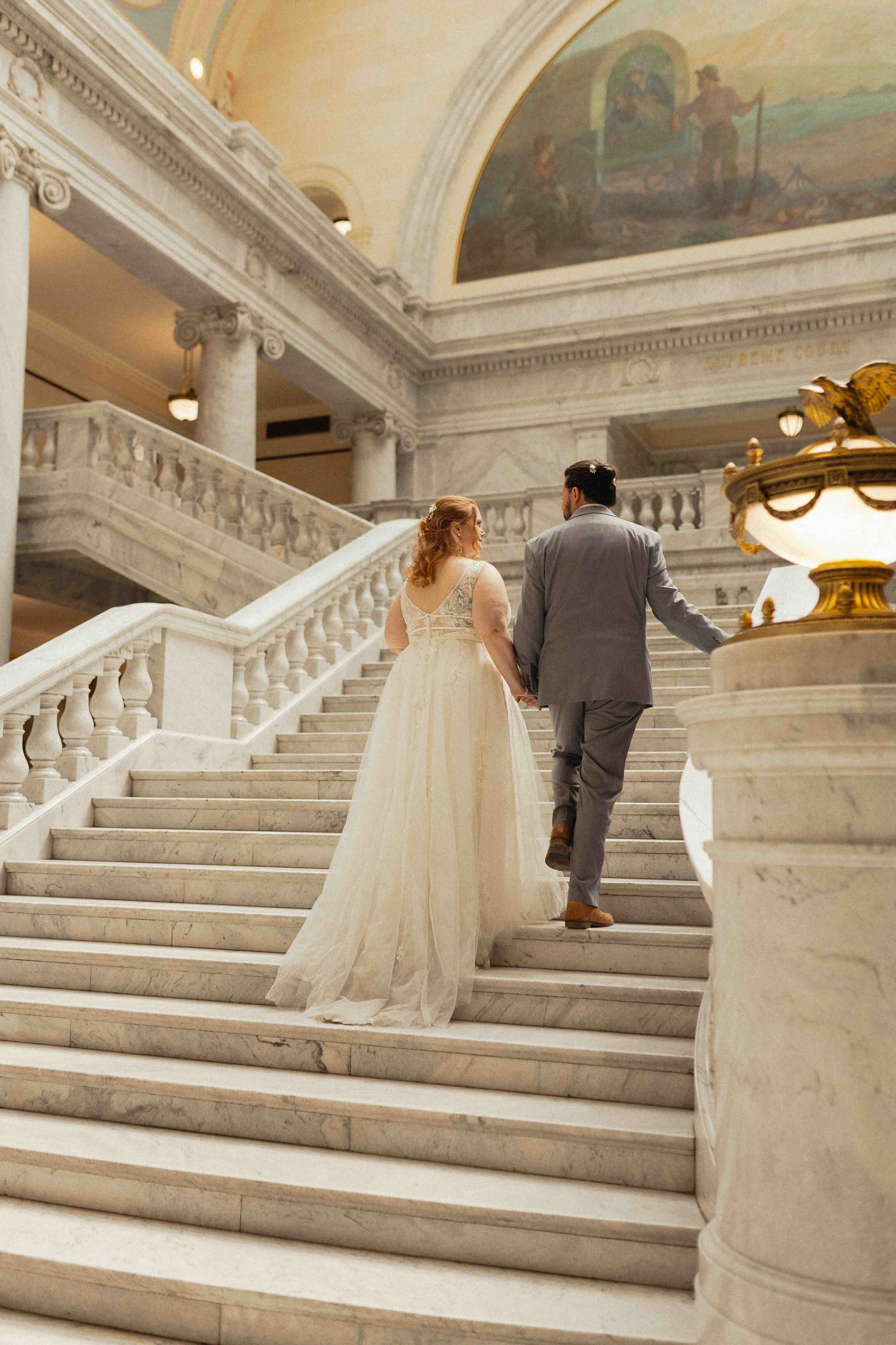 Bride and groom walking up the steps of the Utah State Capitol building.