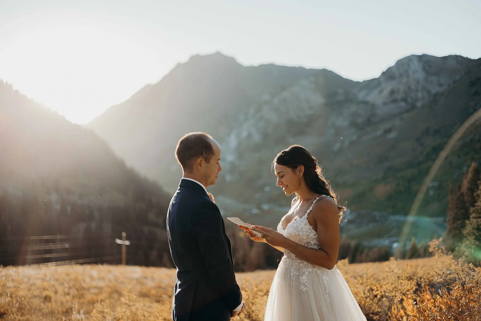 Bride and groom reading a letter on a mountain top.
