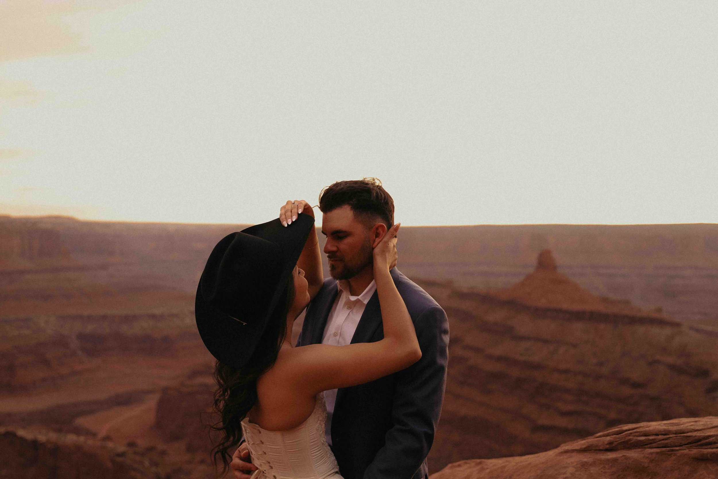 Cowgirl bride putting her hand on her grooms neck in the dessert.