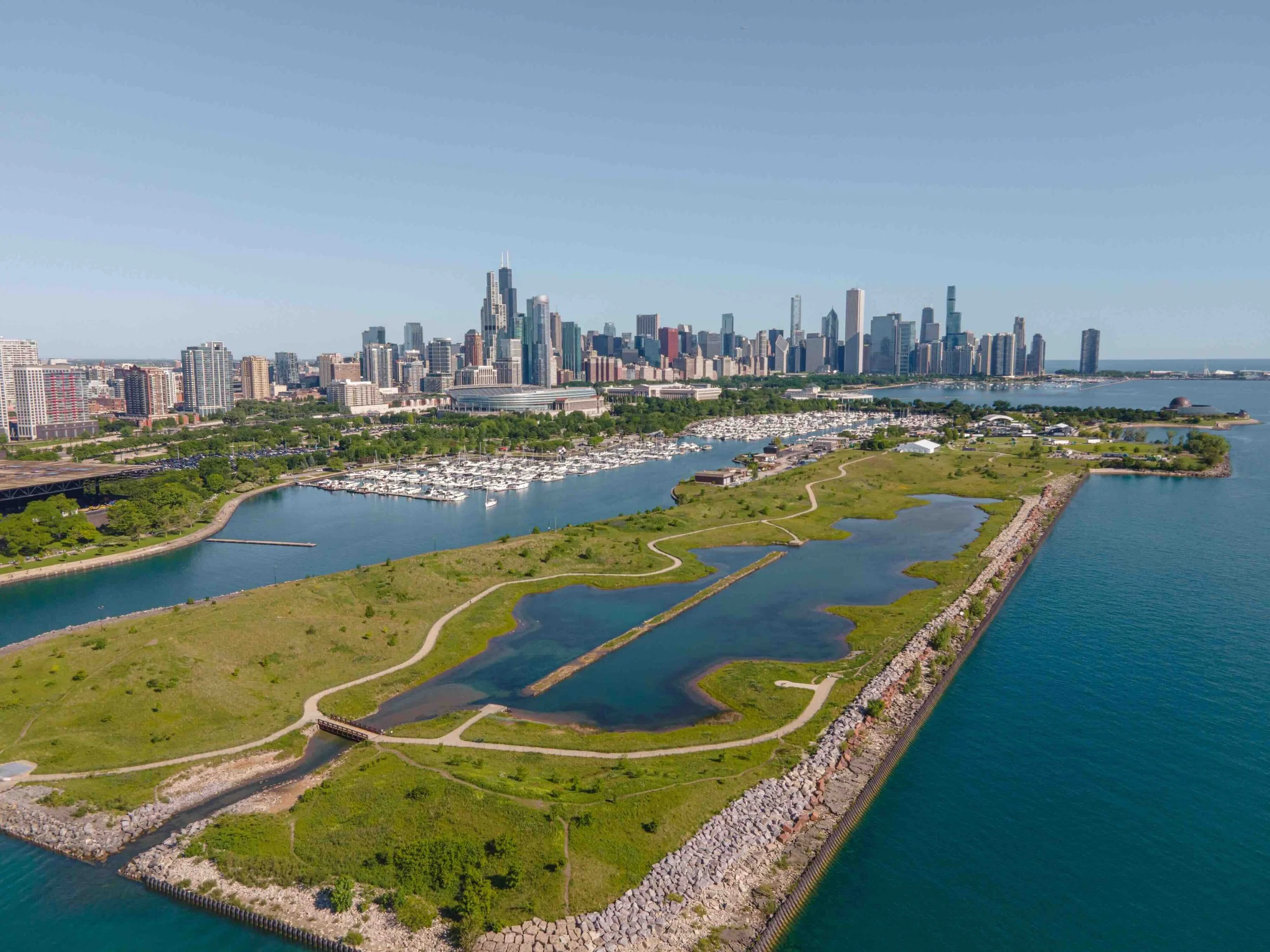 A grassy land mass that juts out into Lake Michigan with the Chicago skyline in the background.