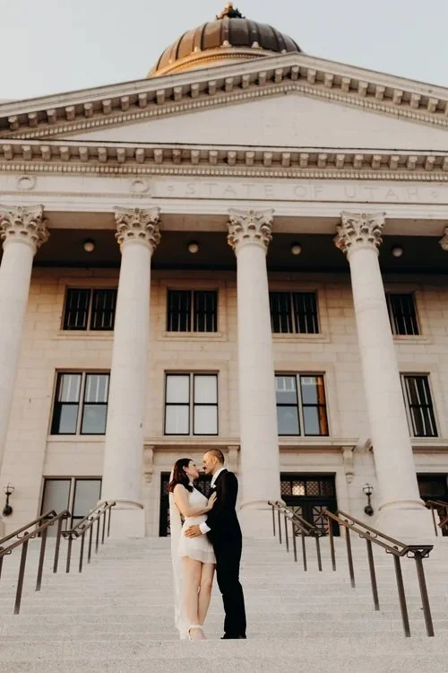Bride and groom standing in front of a capitol building with stairs and columns