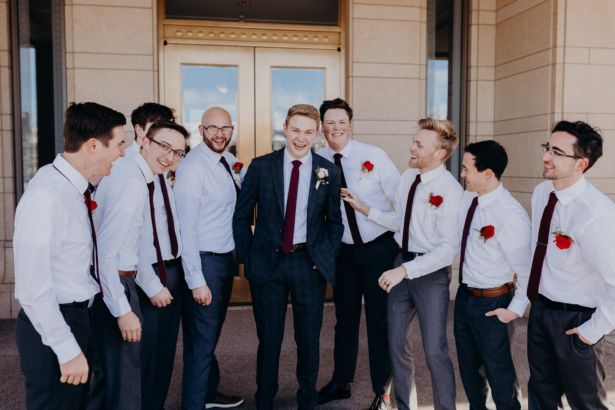 Groomsmen laughing in front of golden doors