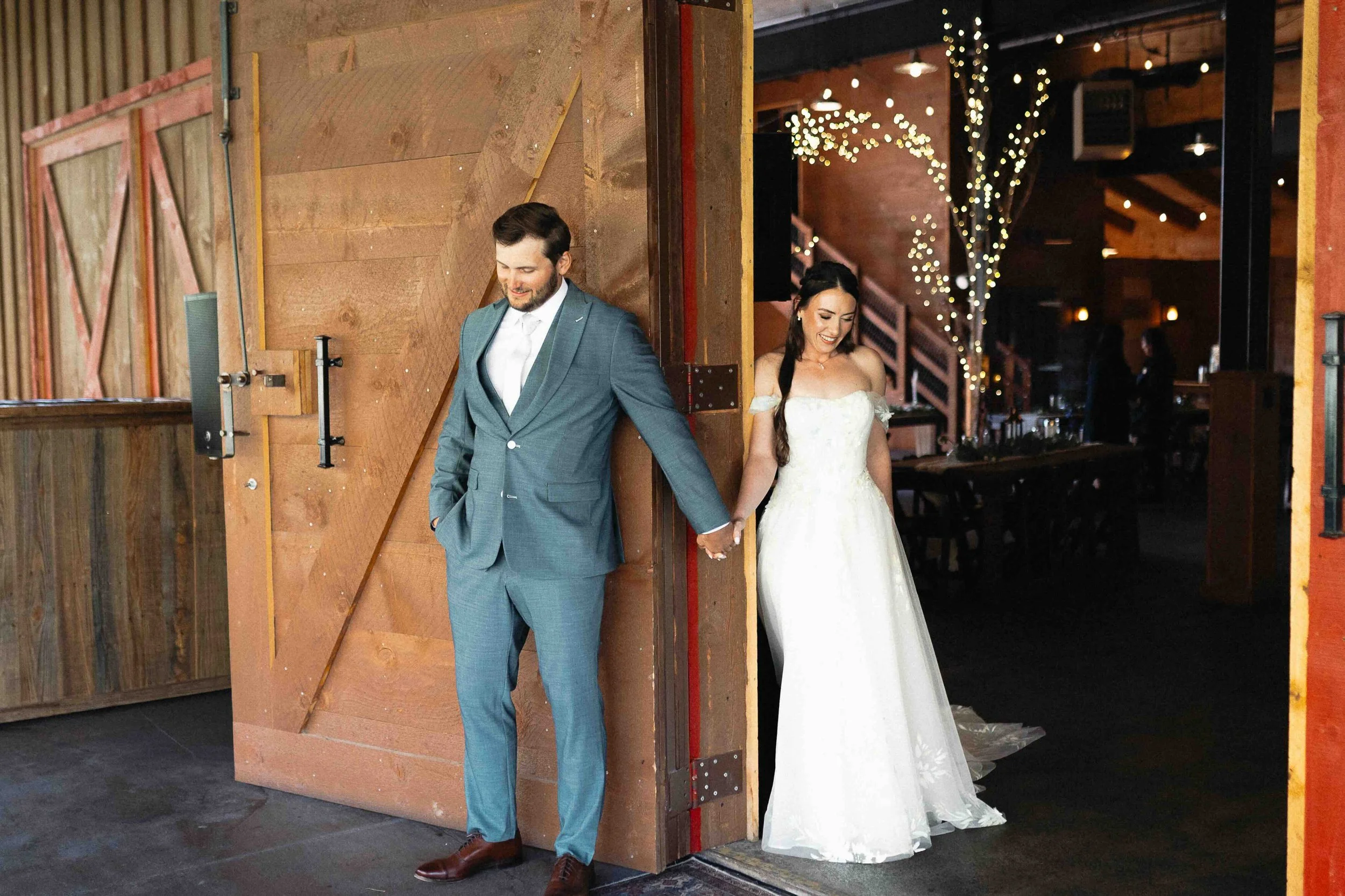 Bride and groom holding hands on opposite sides of a door for their first touch.