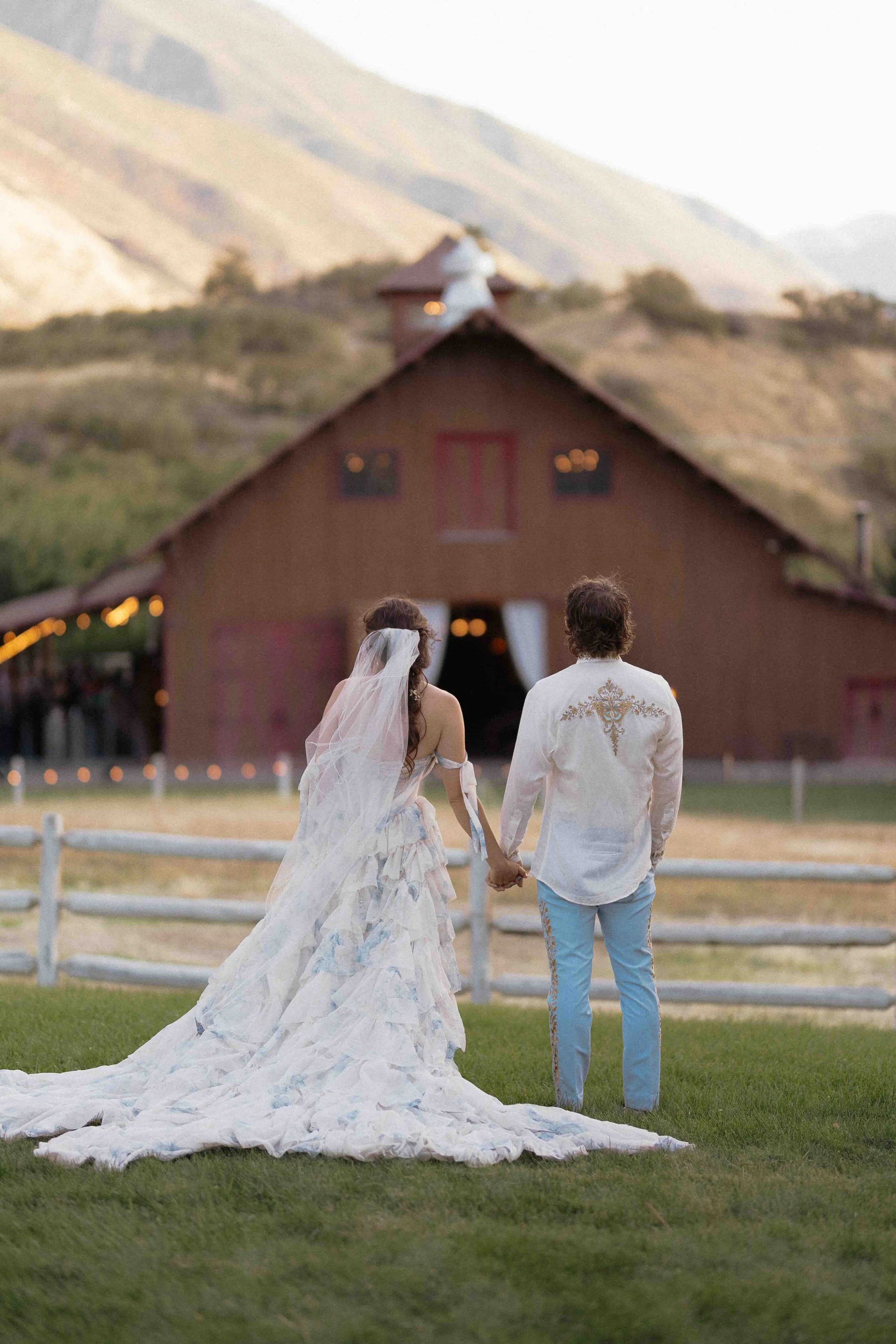 bride and groom looking at barn with mountains in the background.