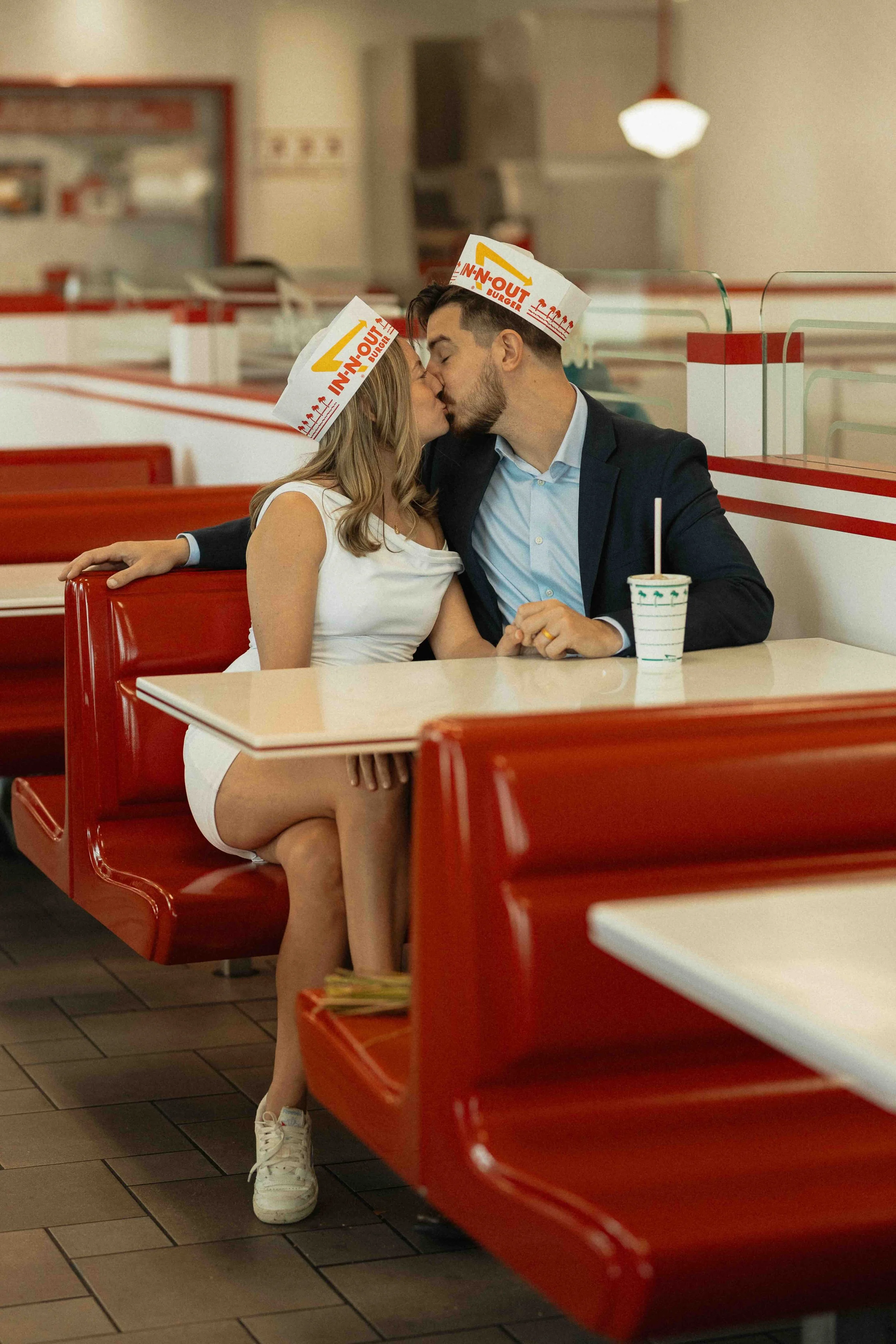 Bride and groom kissing at a vintage burger joint booth.