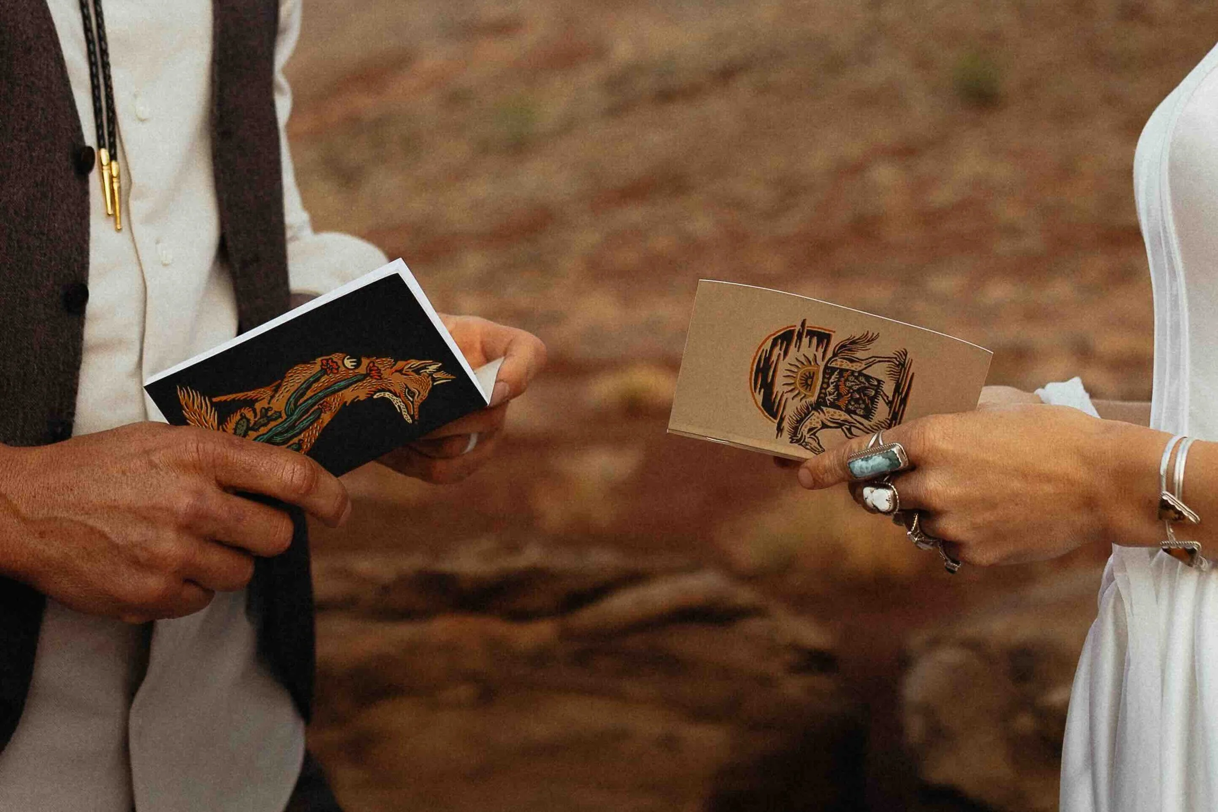 a bride and groom holding onto their vow books in front of the red moab utah dirt.