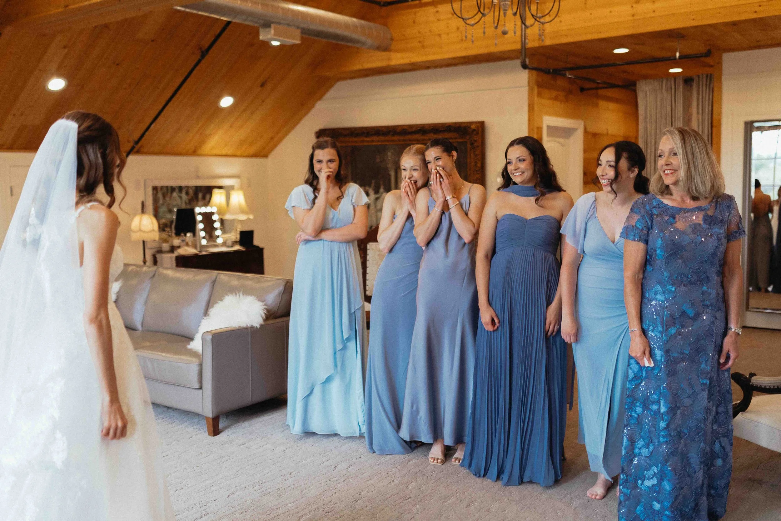 Bride having a first look with her bridesmaids - all dressed in blue gowns.