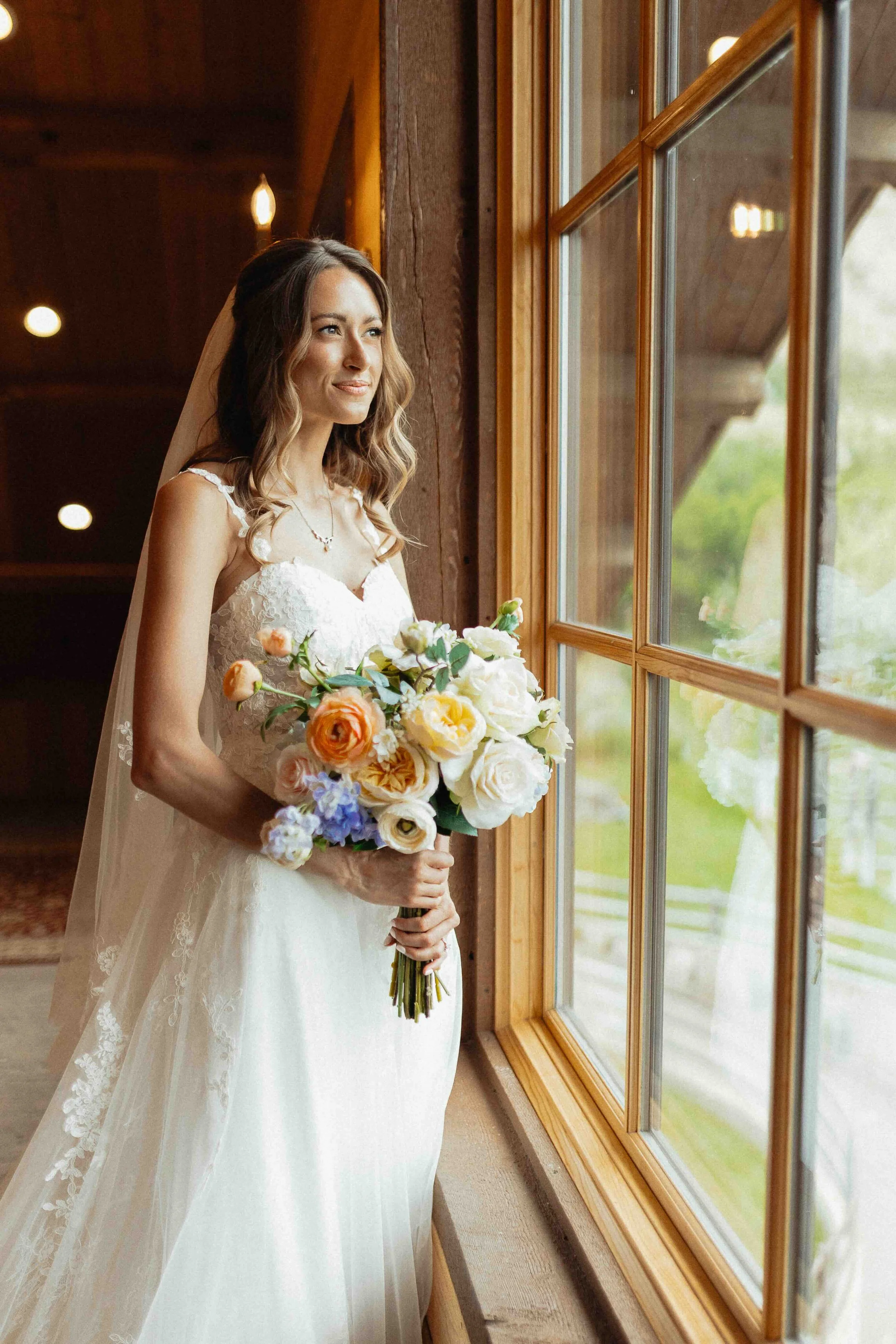 Bride looking out the window at her groom and holding her bouquet.