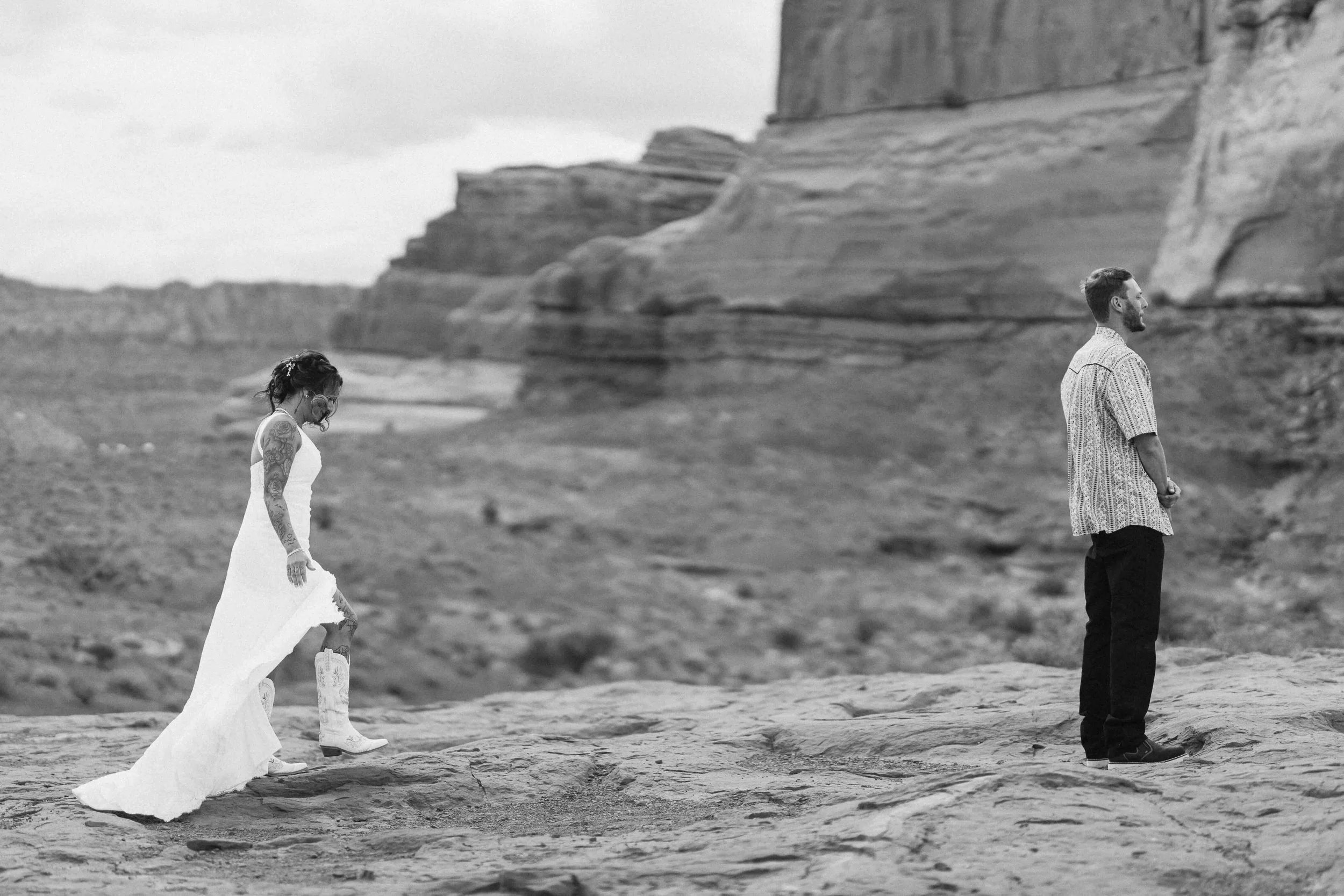 Bride approaching groom for first look in front of rocky cliff sides in Moab.
