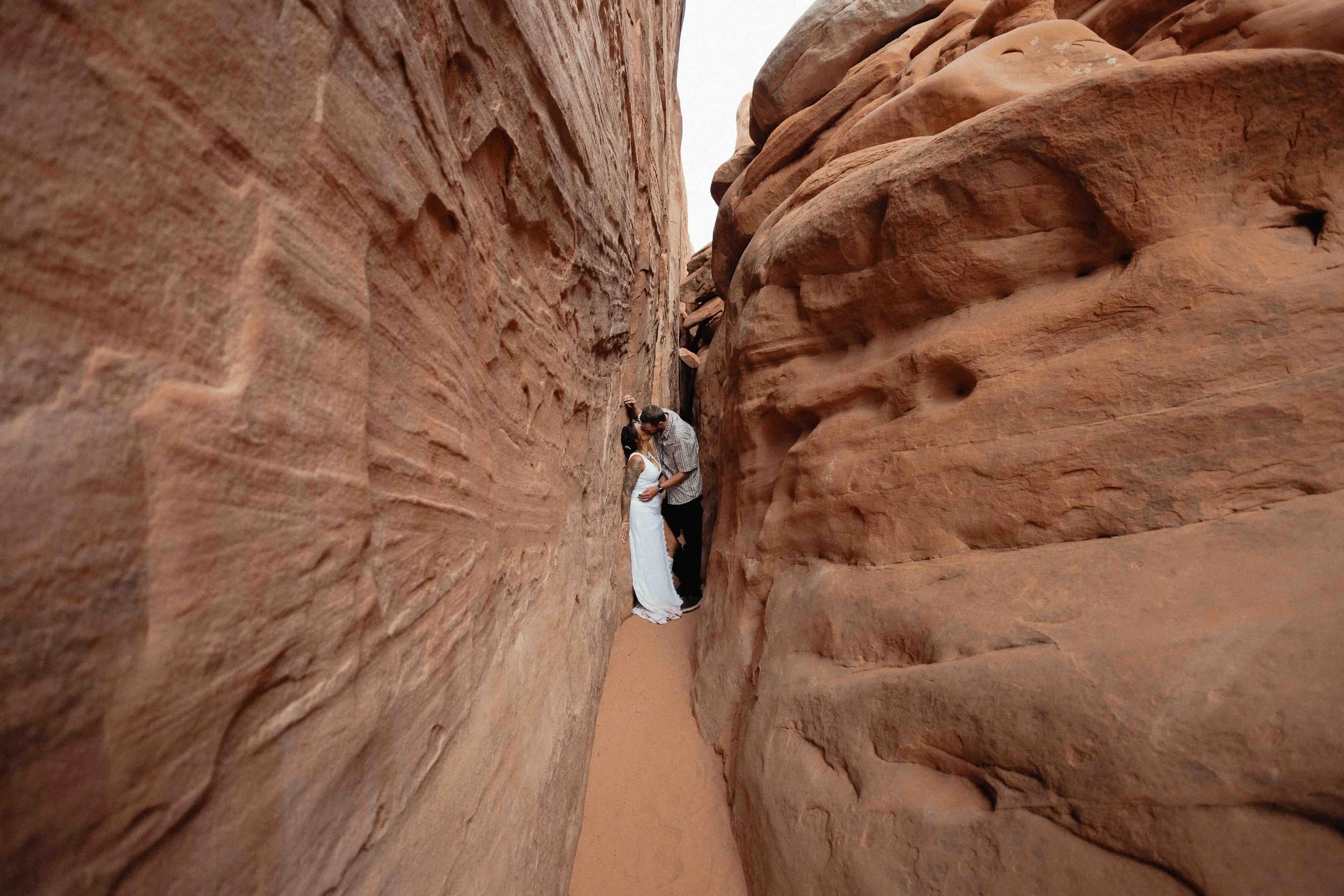Bride and groom standing inside of a slot canyon.