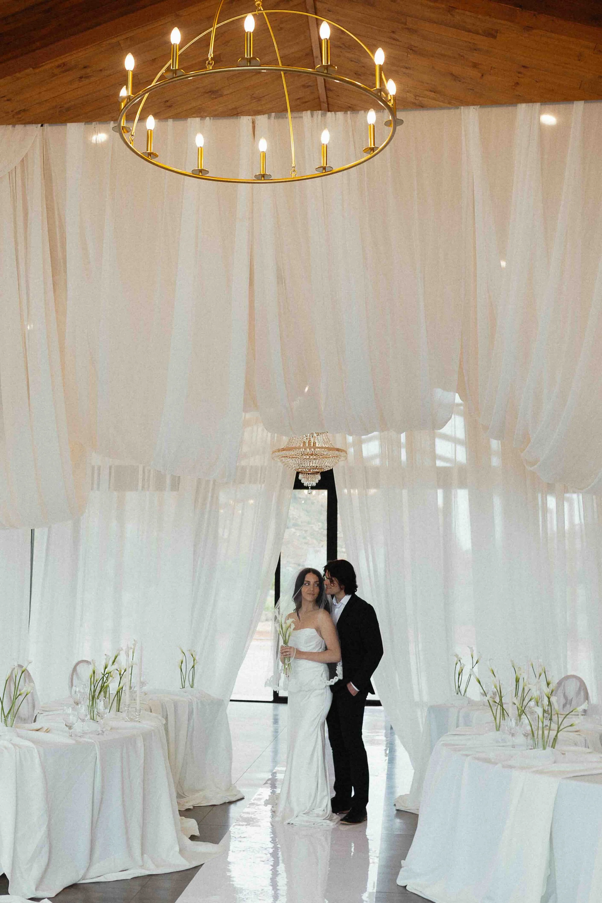 A bride and groom inside a wedding venue drape in white curtains.