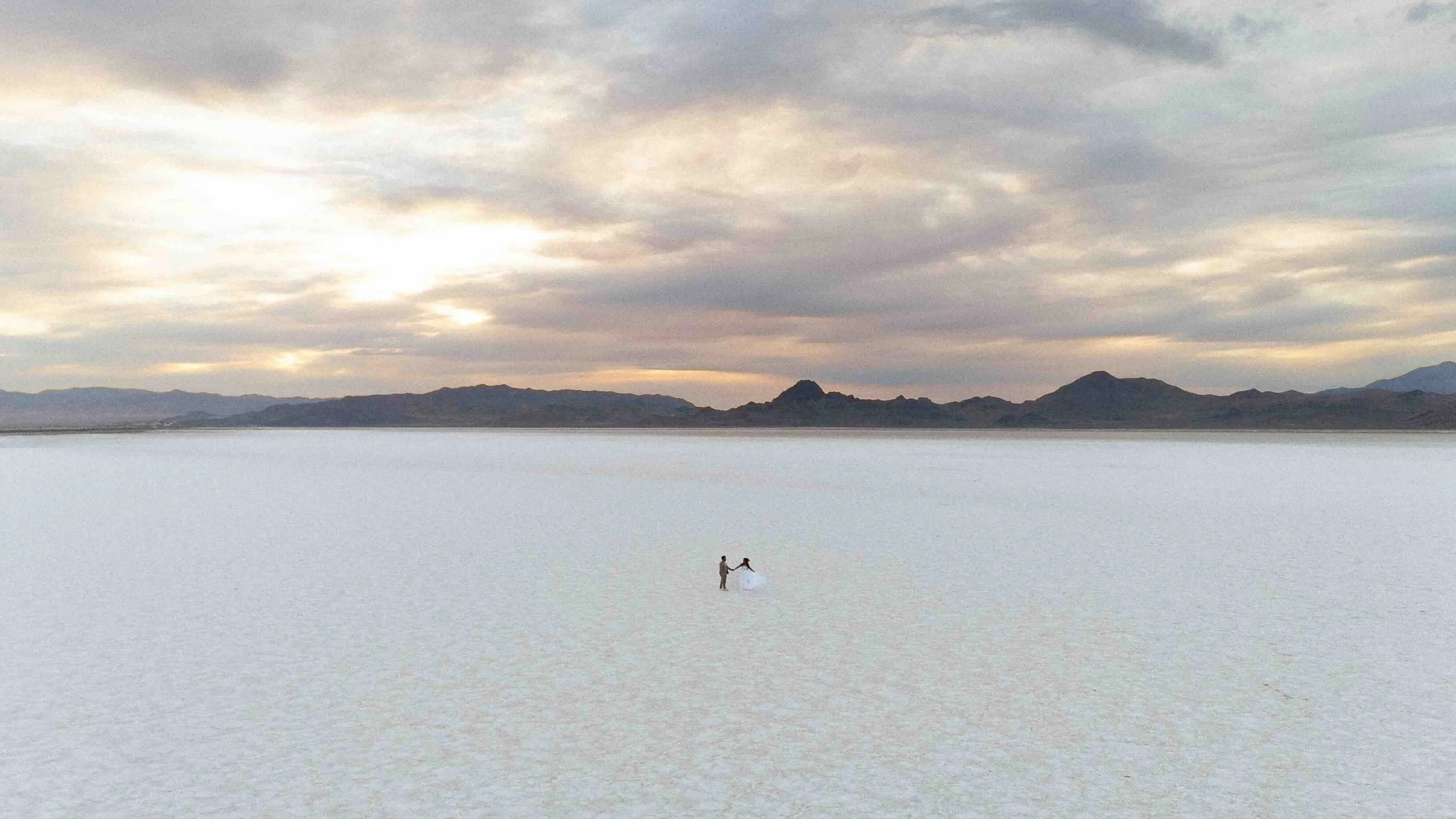 Drone shot of a bride and groom walking along the salt flats of Utah.
