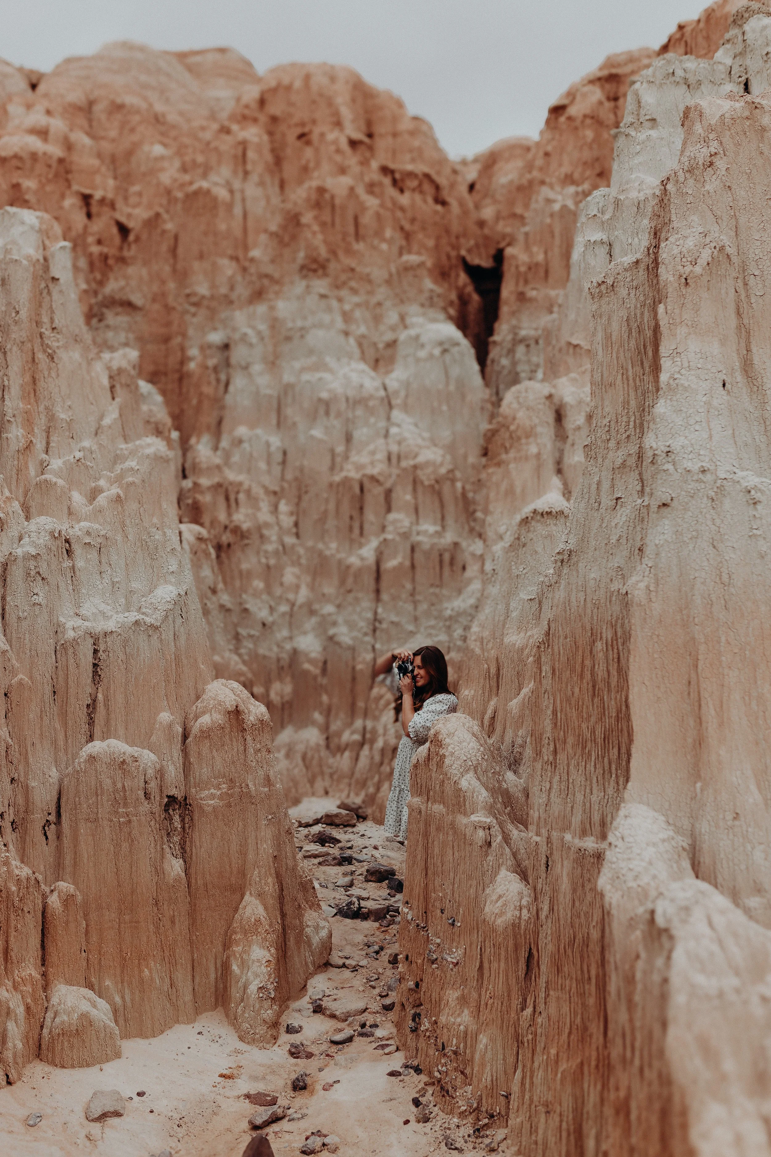 Photographer in white dress taking pictures of Cathedral Gorge State Park rock formations