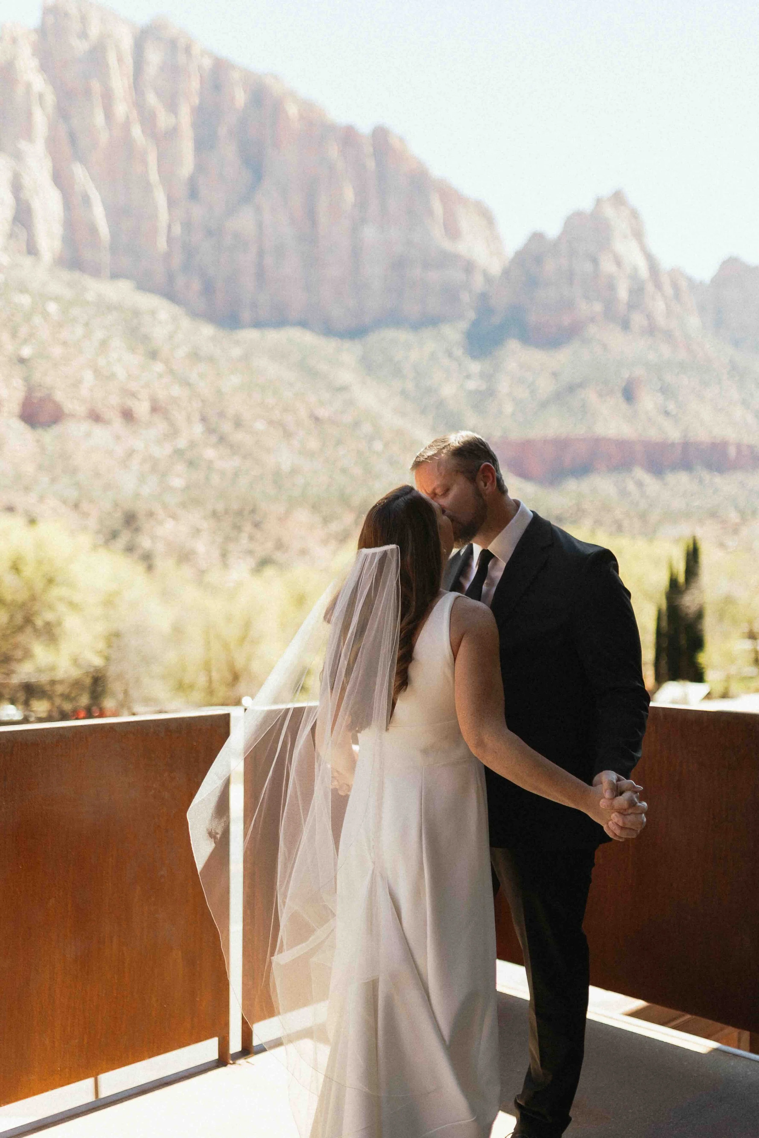 Bride and groom kissing on their patio after their first look. Zion cliff sides in the background.