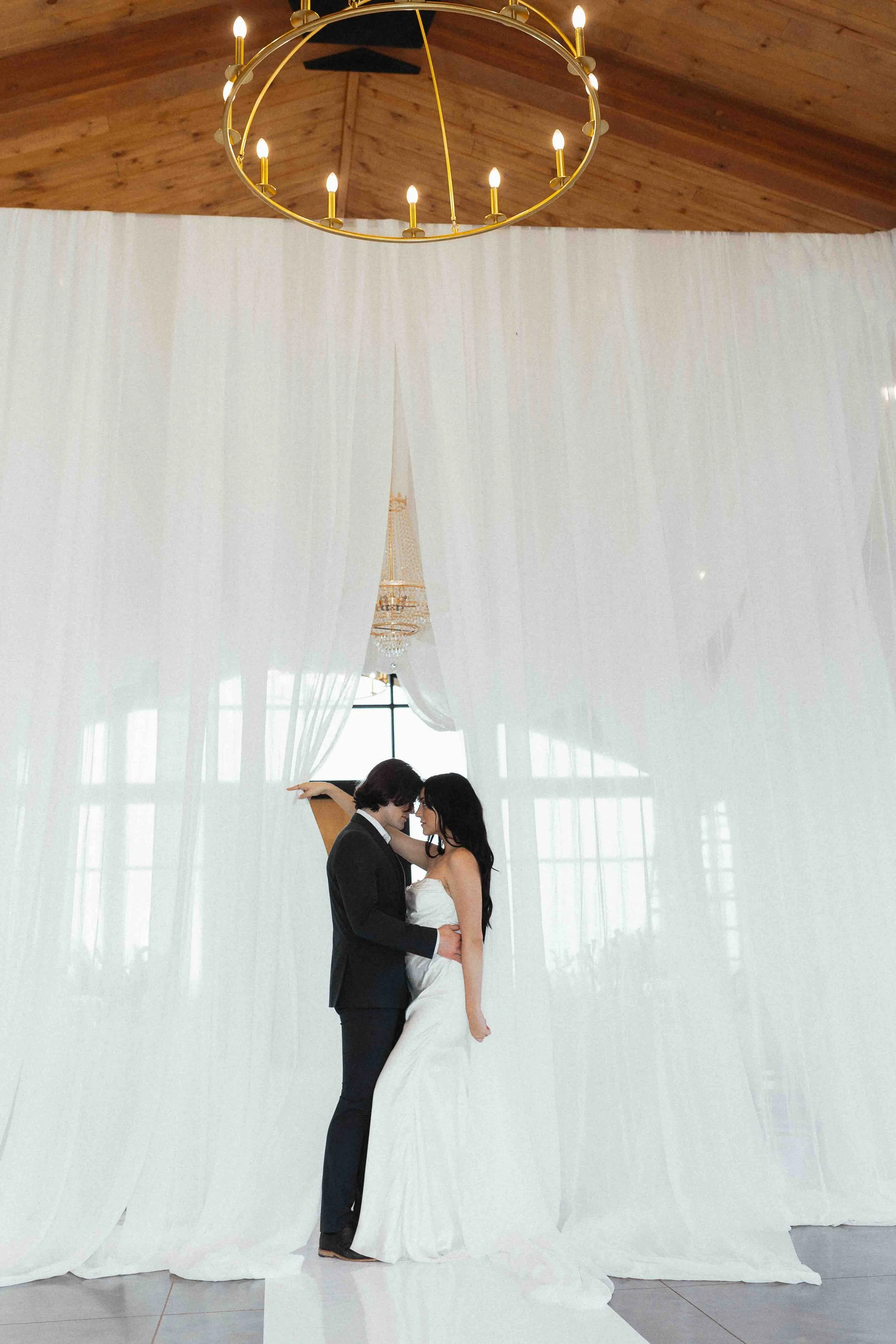 A bride and groom inside a wedding venue drape in white curtains.