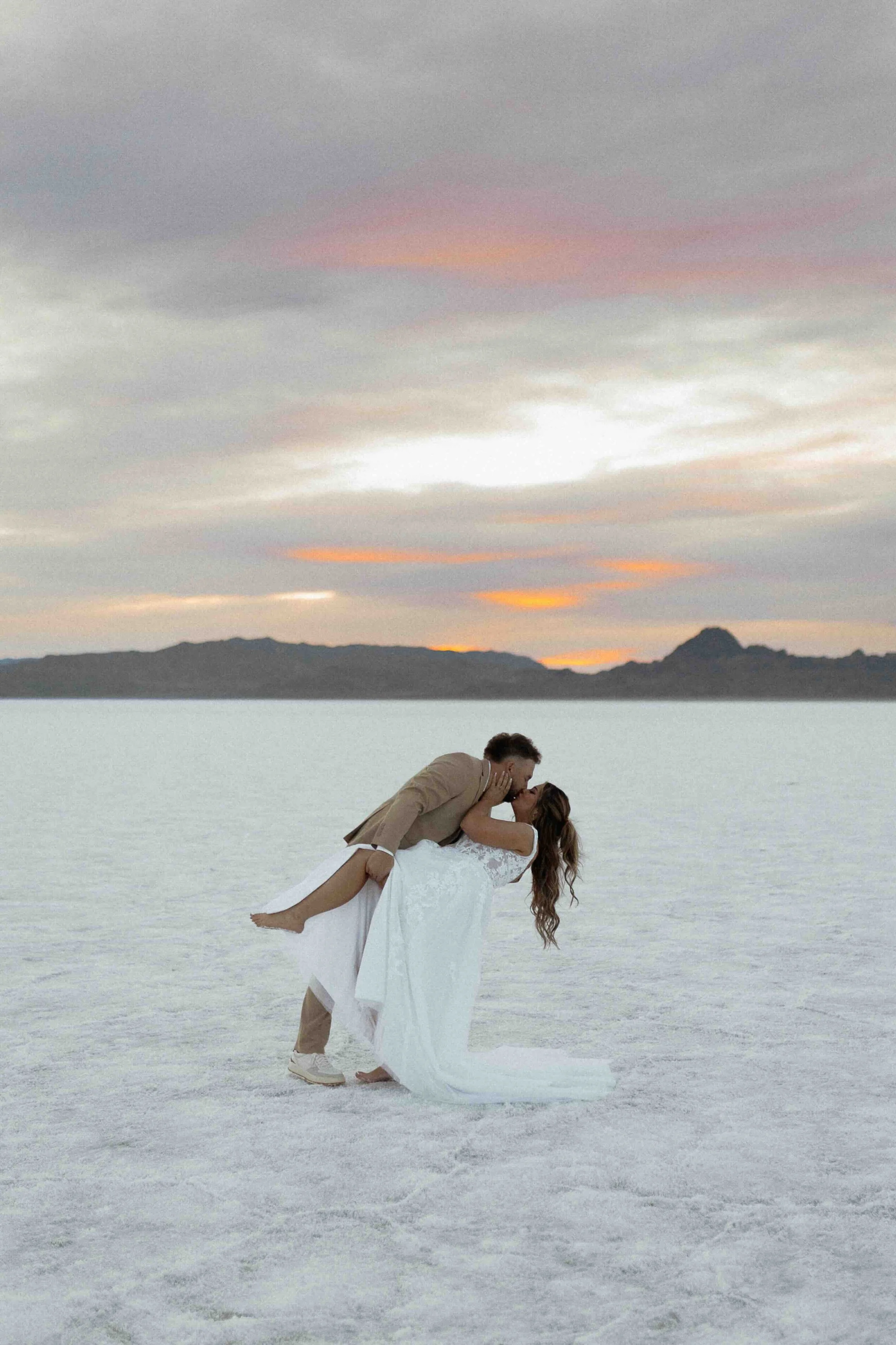 Bride and groom dipping and kissing on the Wenover, UT salt flats.