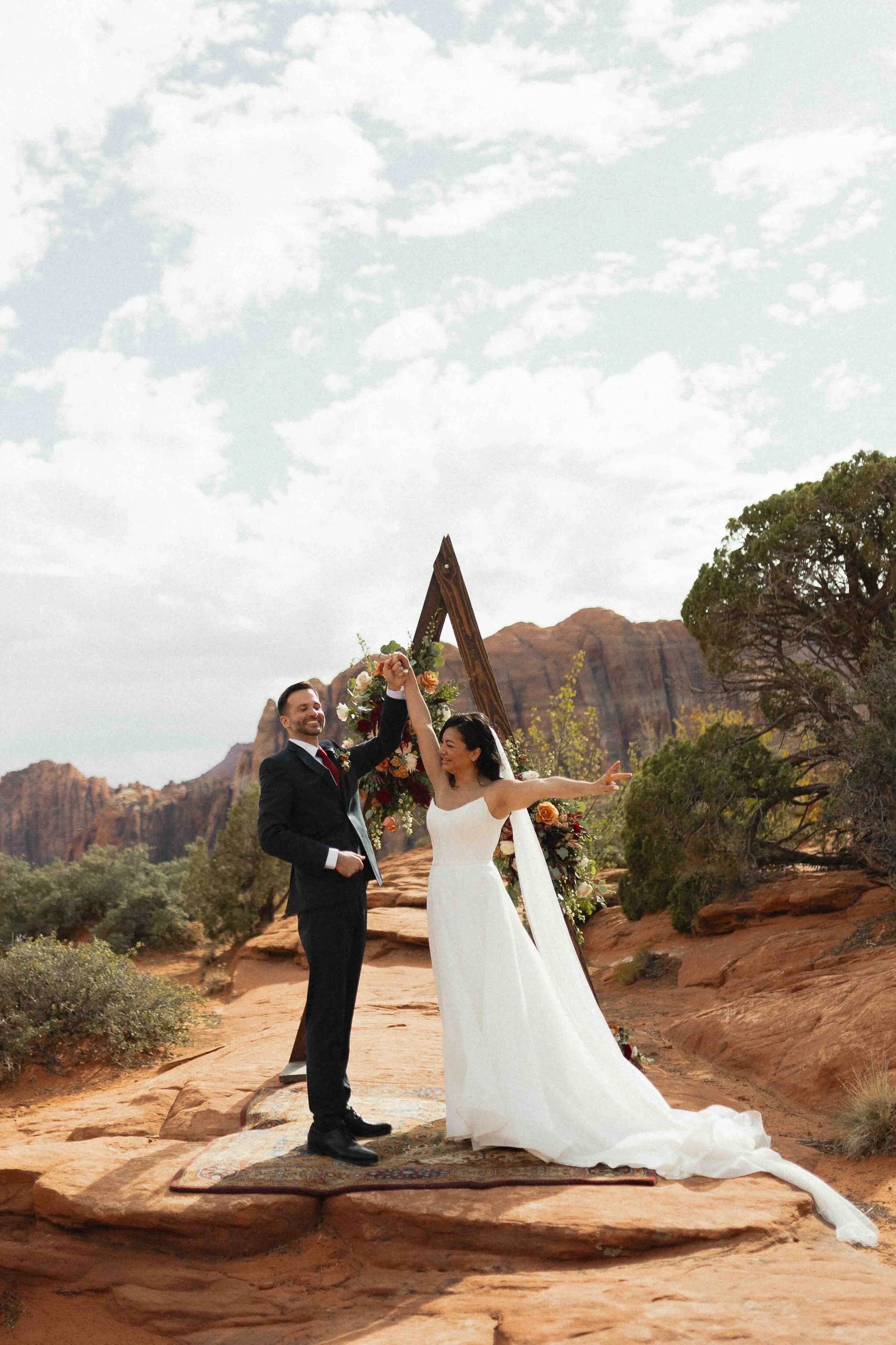 a bride and groom celebrating at a triangular arch in Utah in front of petrified dunes.