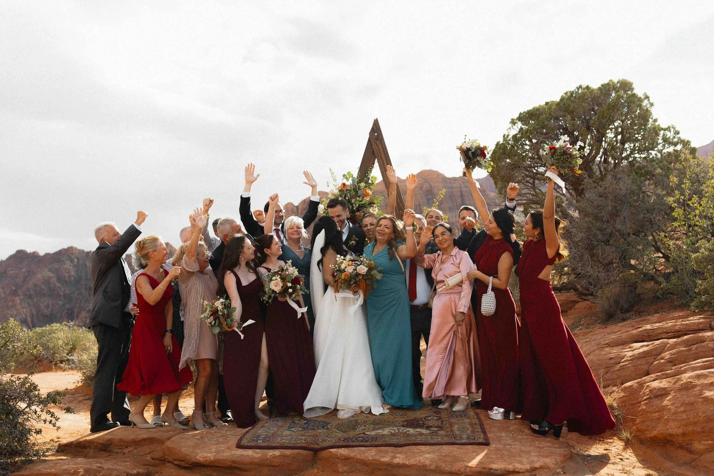 a family photo of guests cheering on the red rock of Utah.