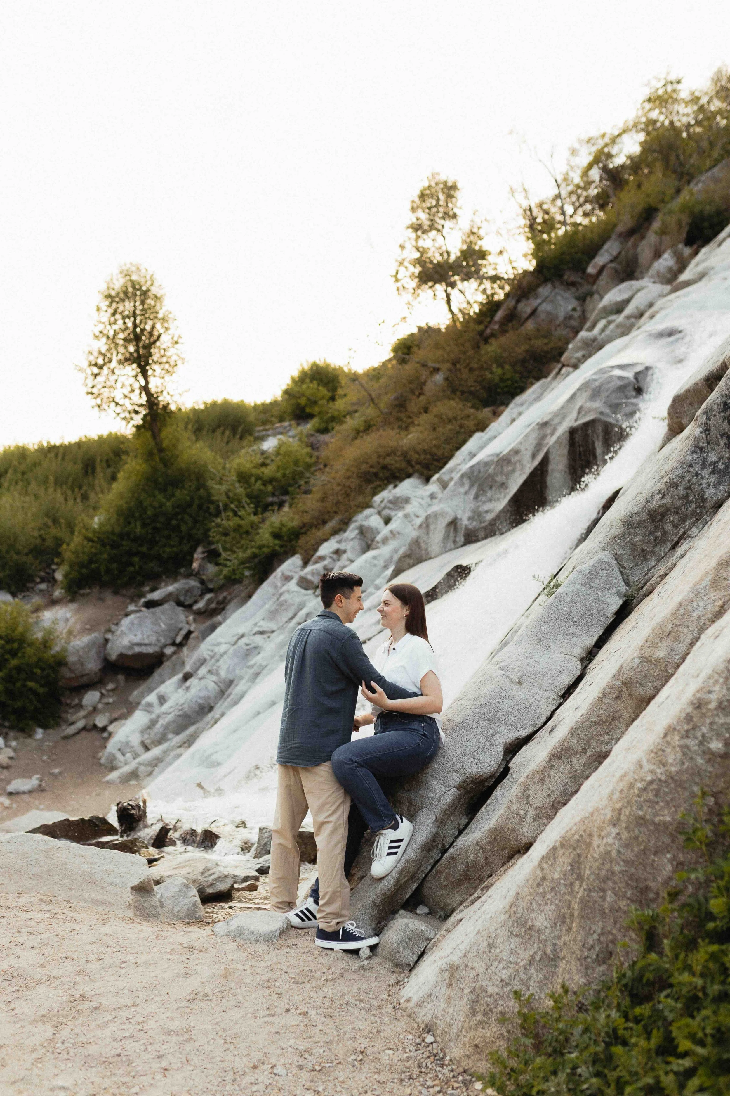 Couple embracing in front of waterfall.
