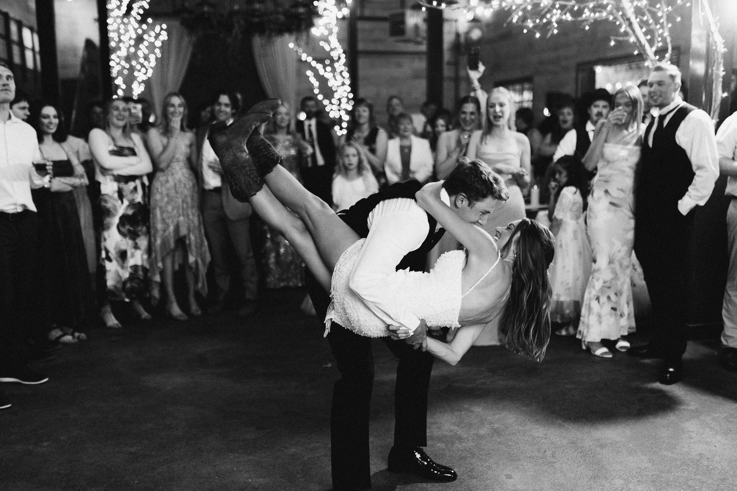 Bride and groom country swing dancing in front of all of their guests at their reception in a barn.