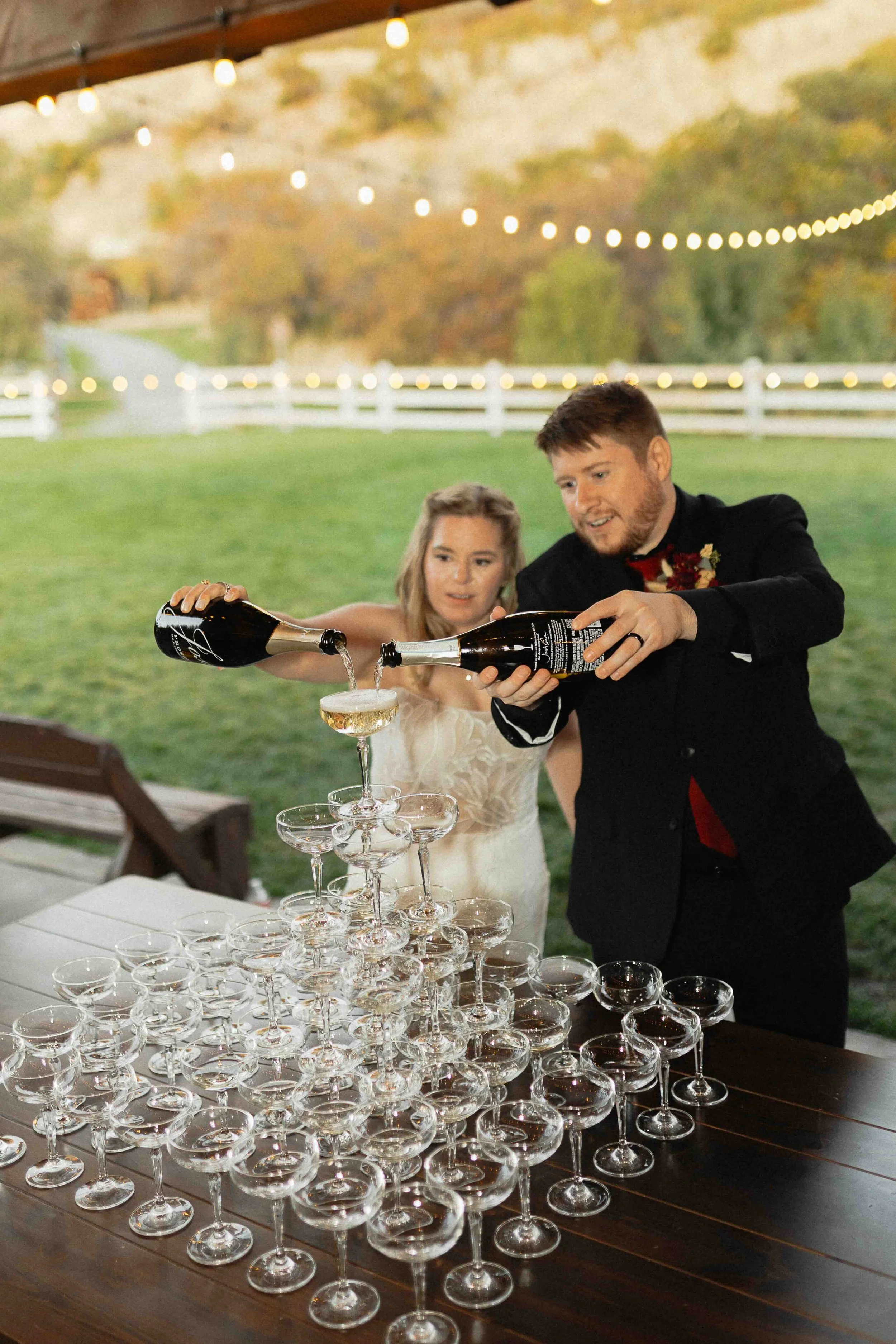 Bride and groom pouring champagne into a champagne tower.