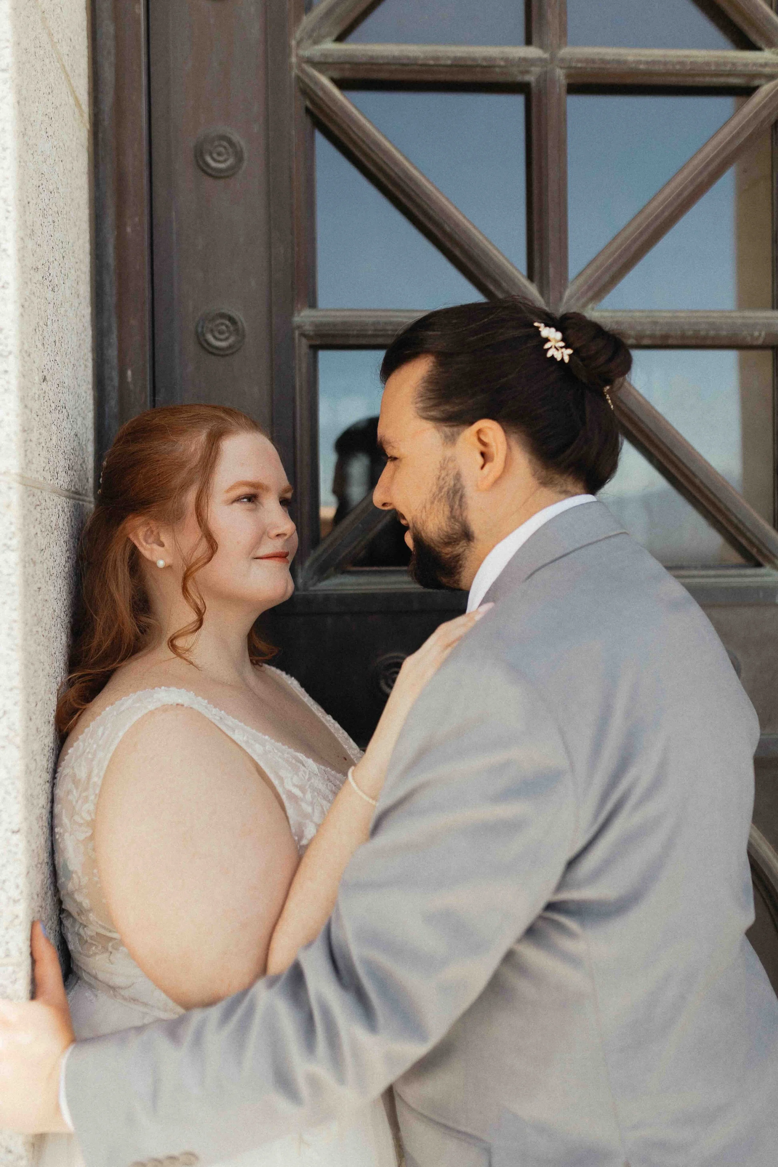 Bride and groom smiling at each other in front of a vintage door.