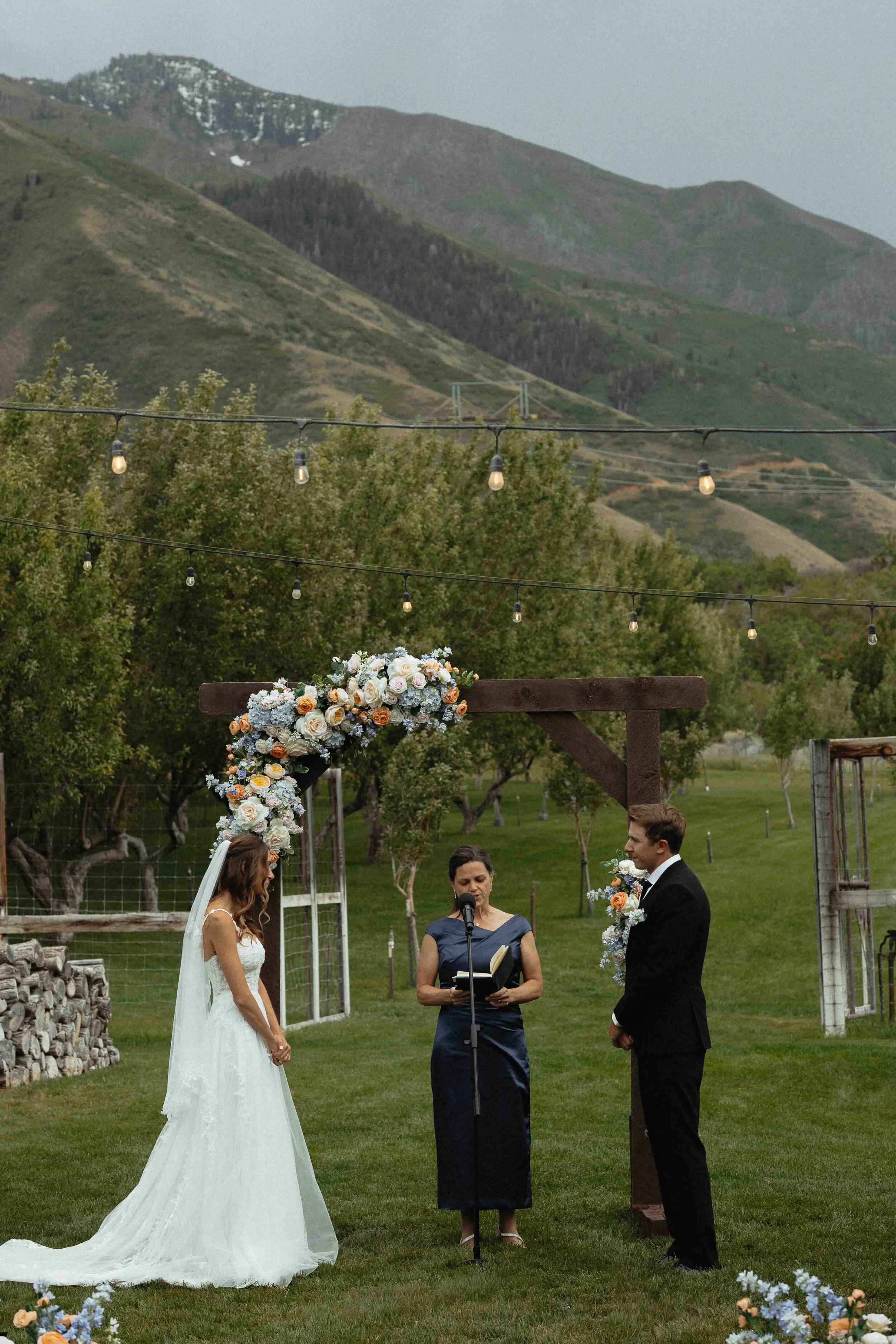 Bride and groom standing at the alter with their officiant in front of the mountains,