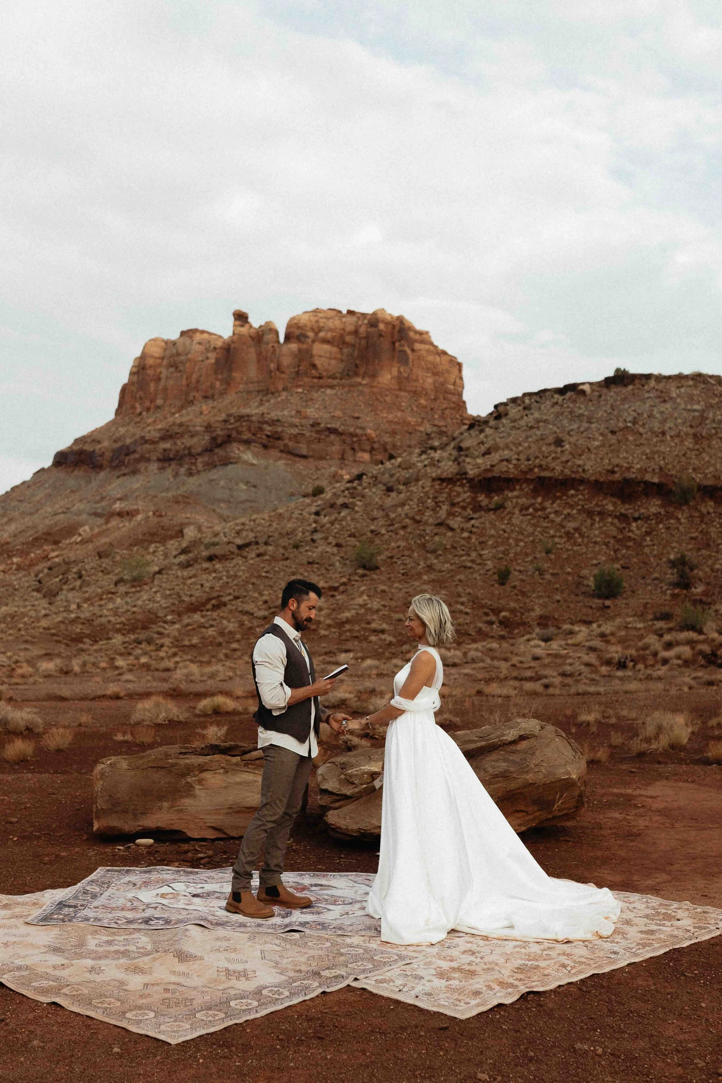 a bride and groom saying their vows in front of moab red rock.