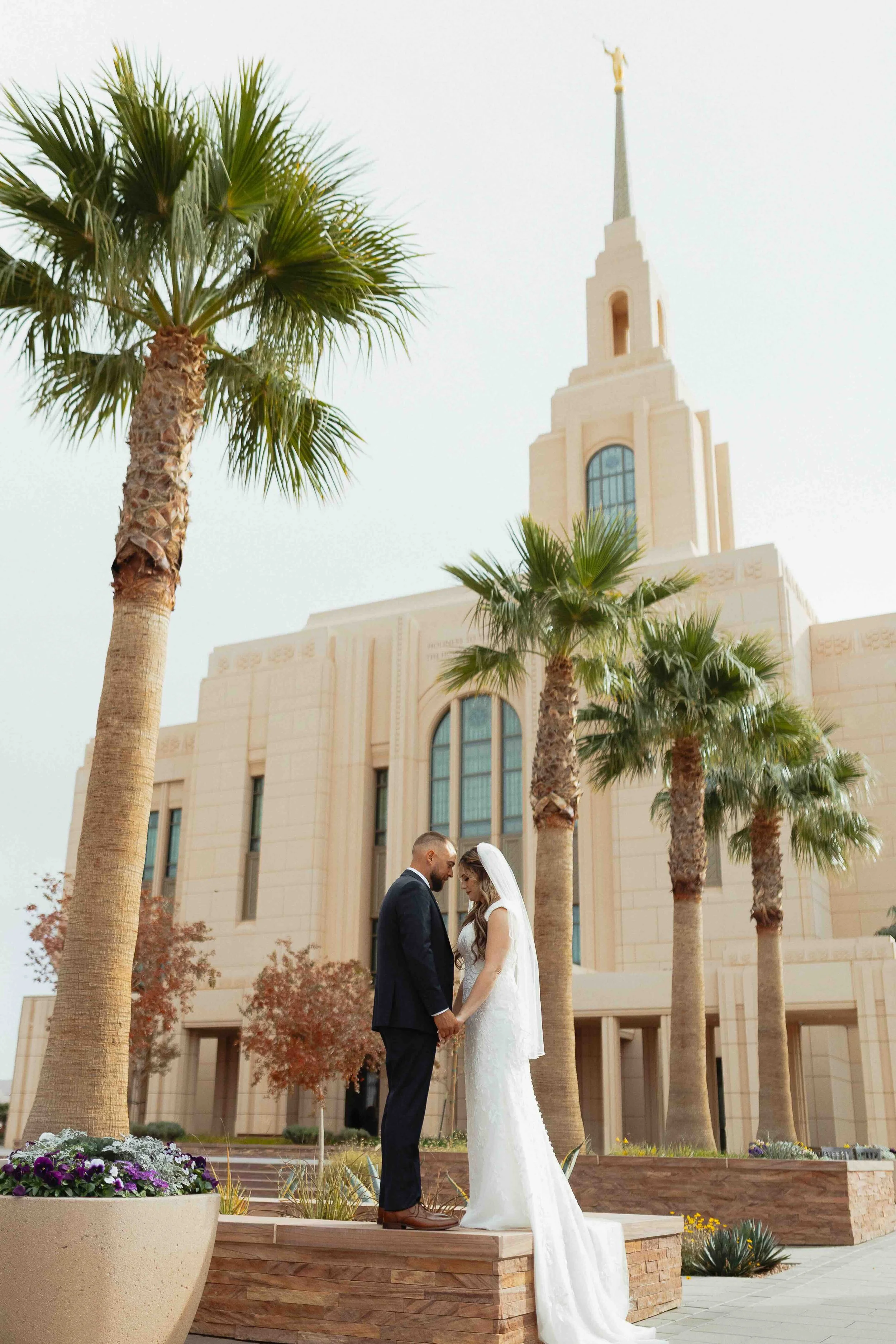 Bride and groom nuzzling foreheads at an LDS temple in St. George with palm tress in the background.
