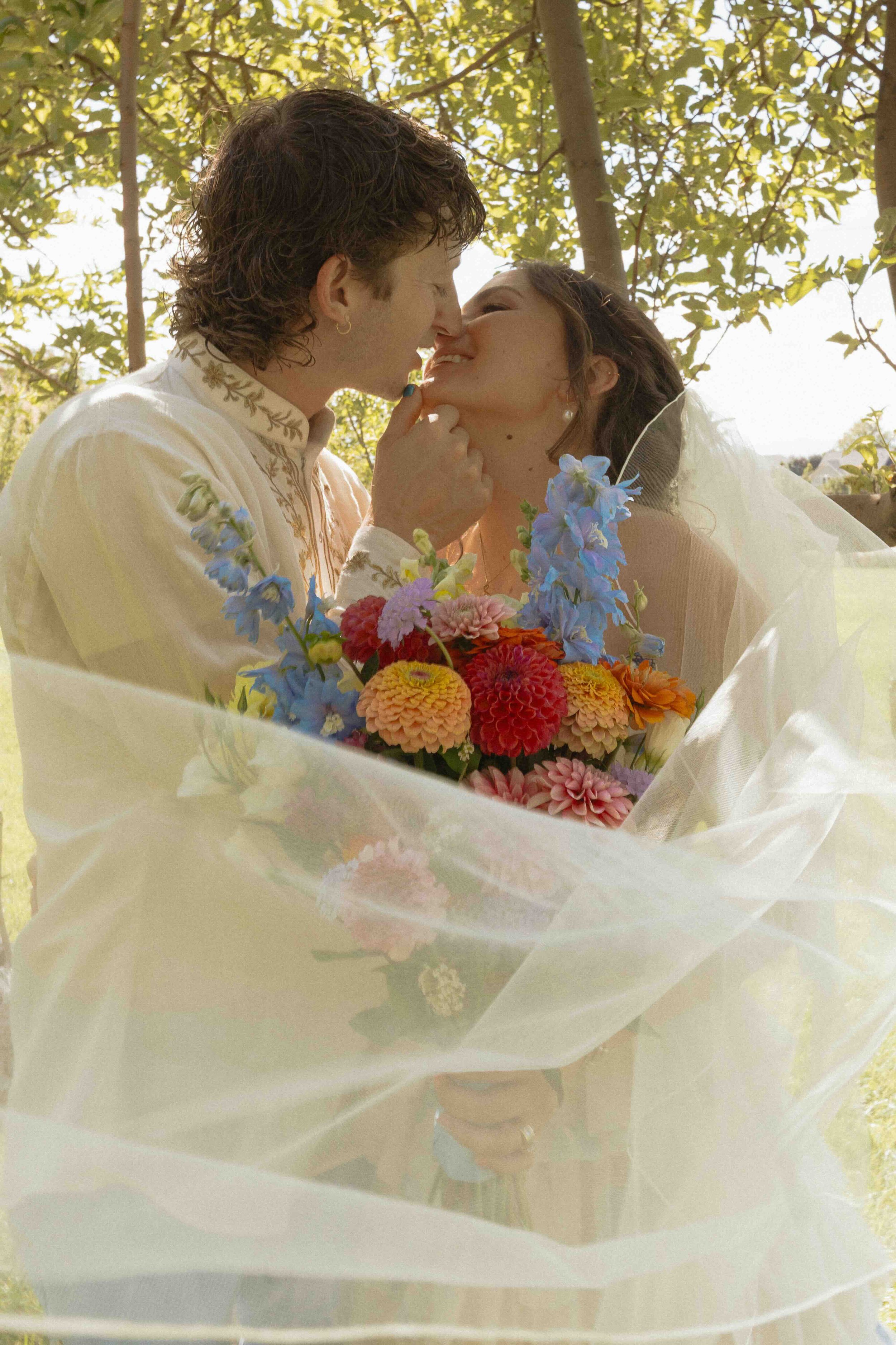 Bride and groom about to kiss with veil floating in foreground.