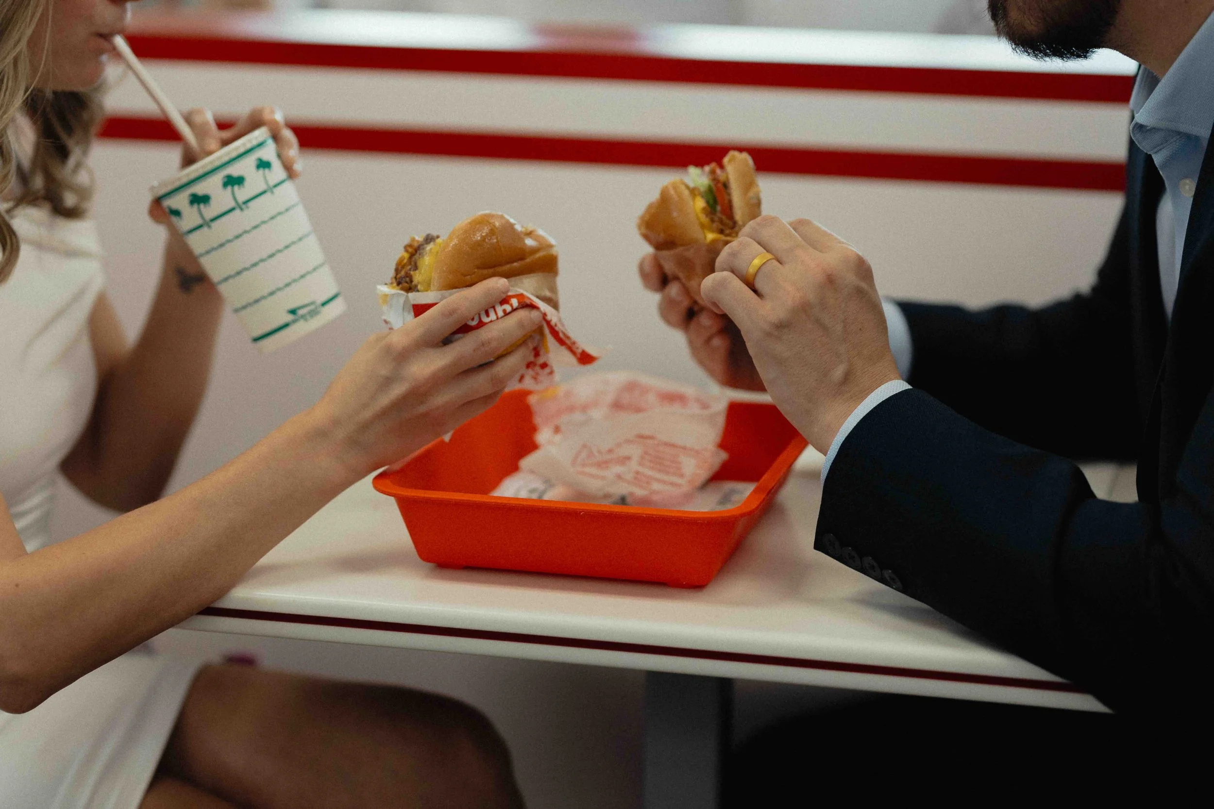 Bide and groom holding burgers after their wedding ceremony.