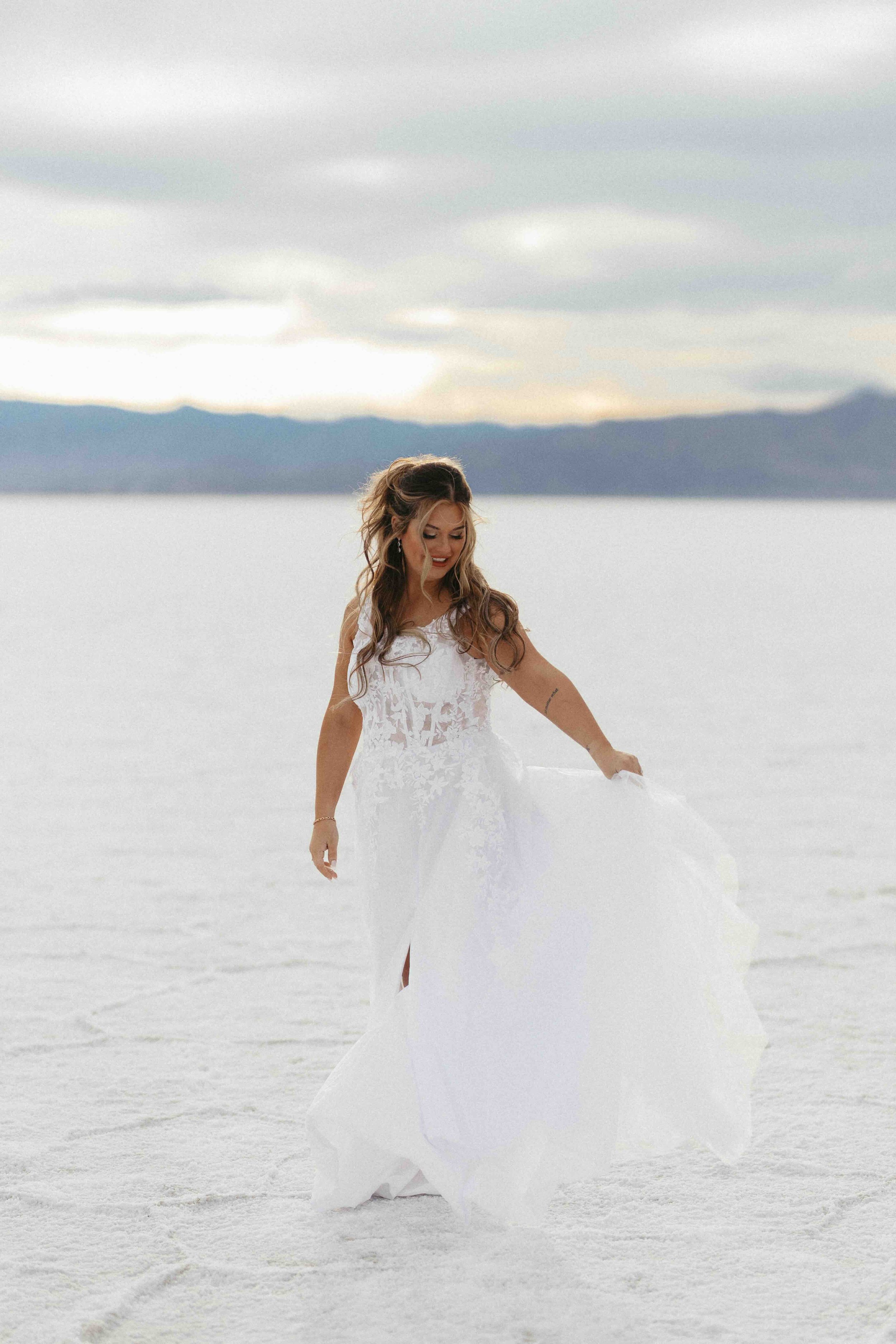 Bride standing of the salt flats of utah with mountains in the background.