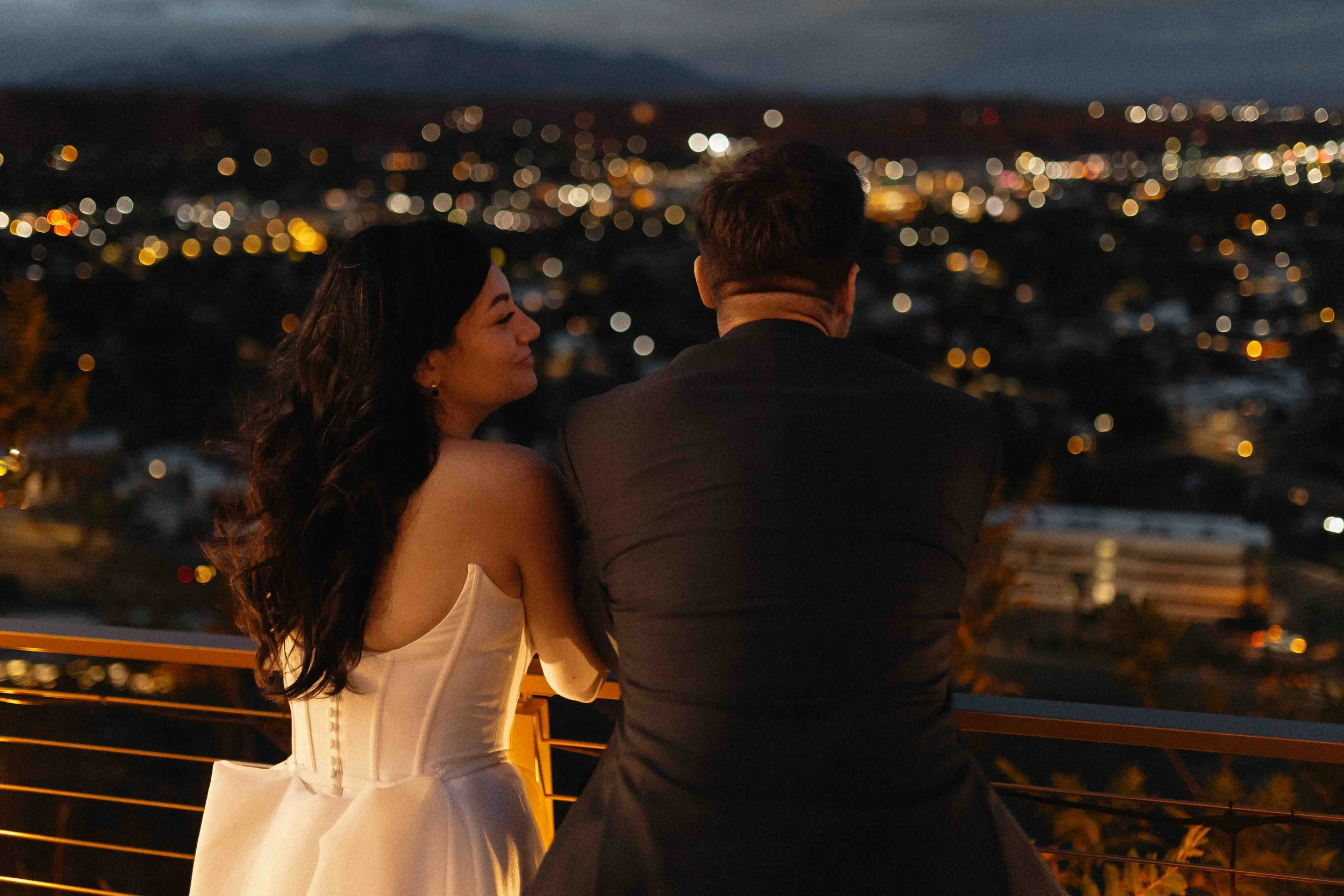 a bride and groom overlooking the city lights.