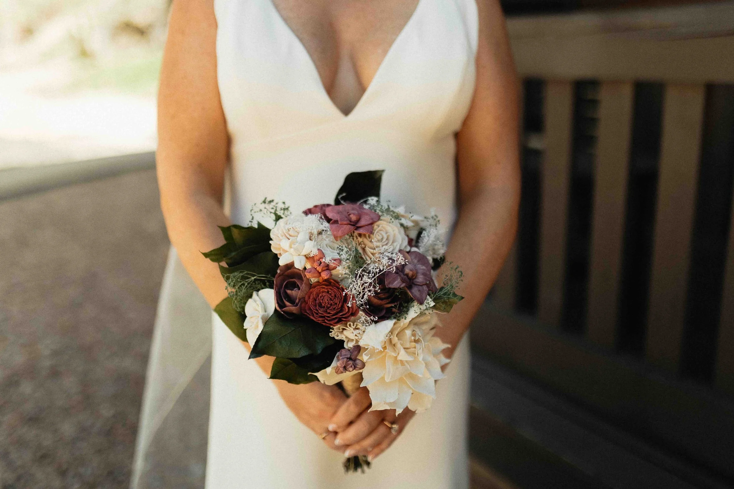 Bride holding onto her wooden bouquet in front of a lodge.