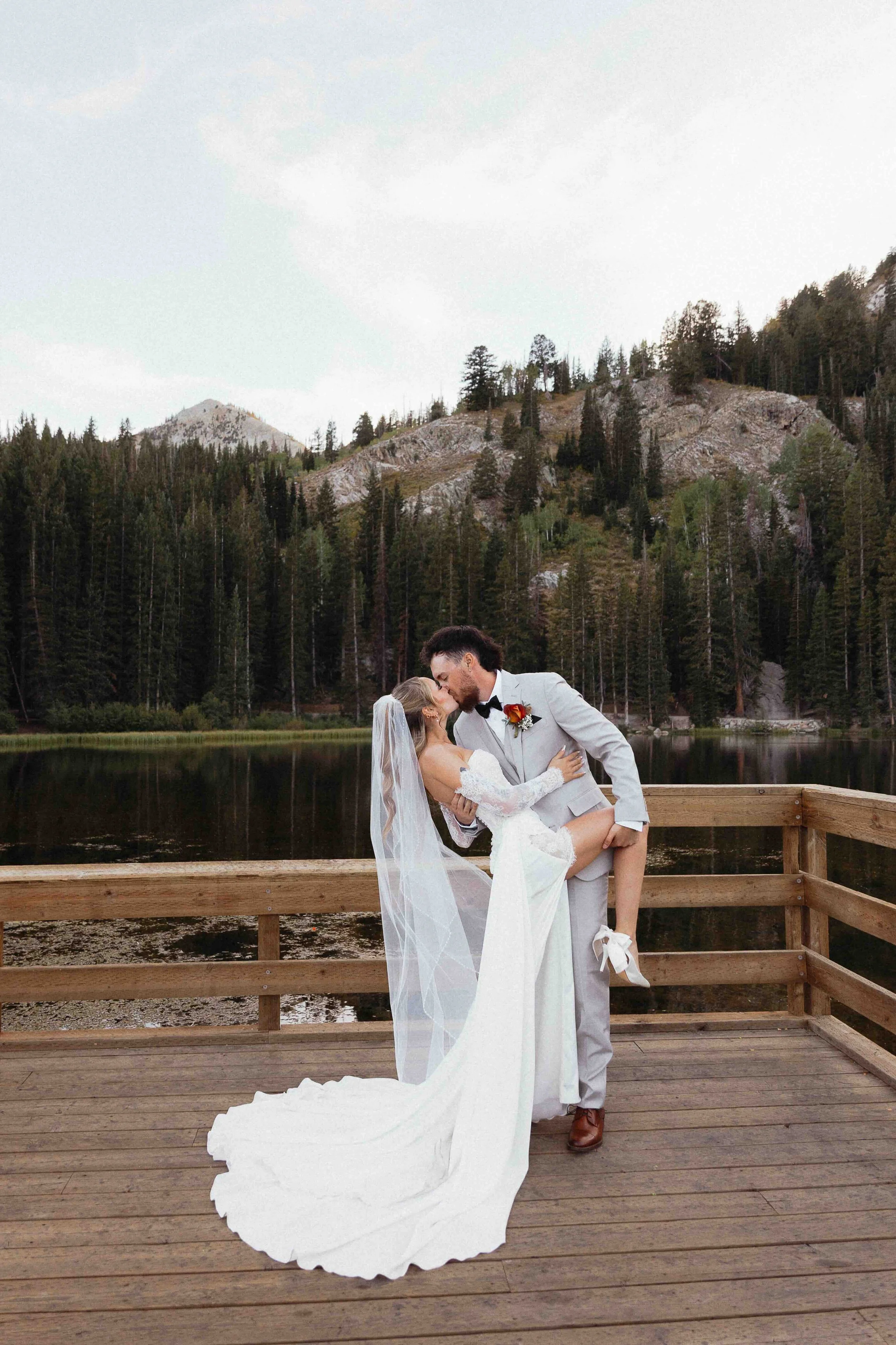 Bridal couple dipping in front of water and mountain tops on a deck.