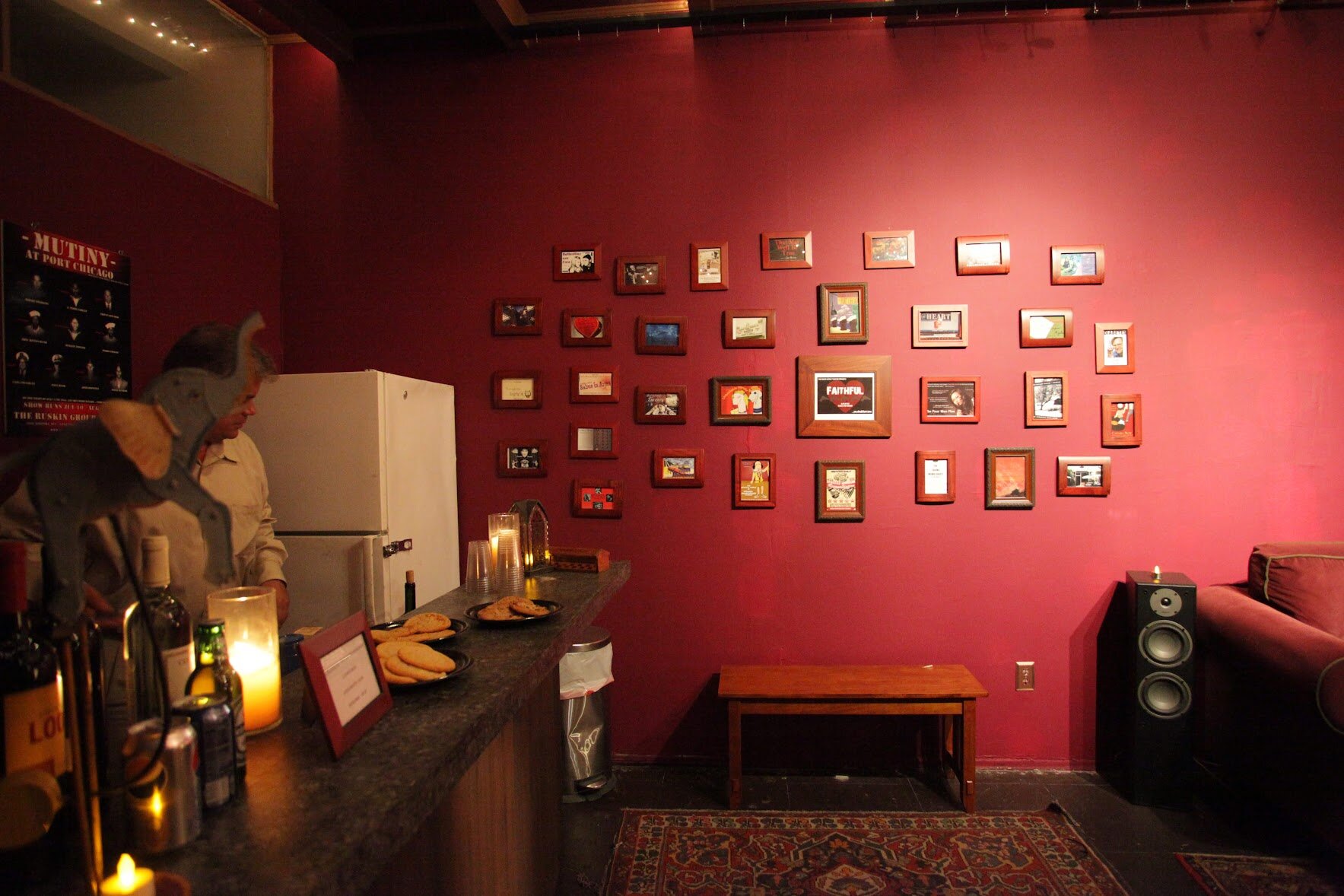 A Burgundy wall with playbills and a bar
