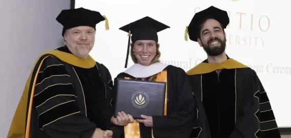 Sentio University MFT graduate at the inaugural commencement ceremony with faculty