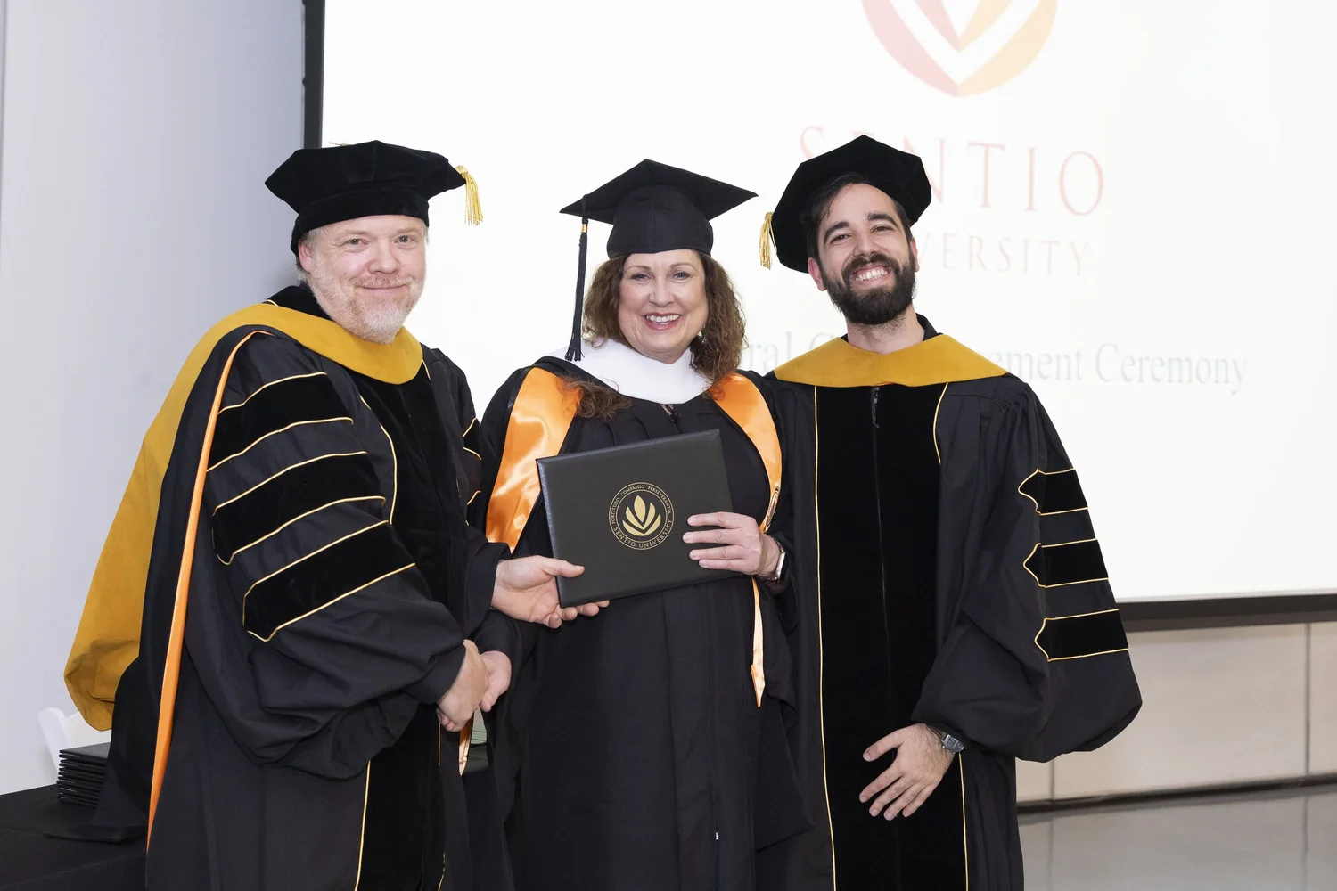 Sentio University MFT graduate Michele Carroll with Sentio faculty at the 2026 commencement ceremony