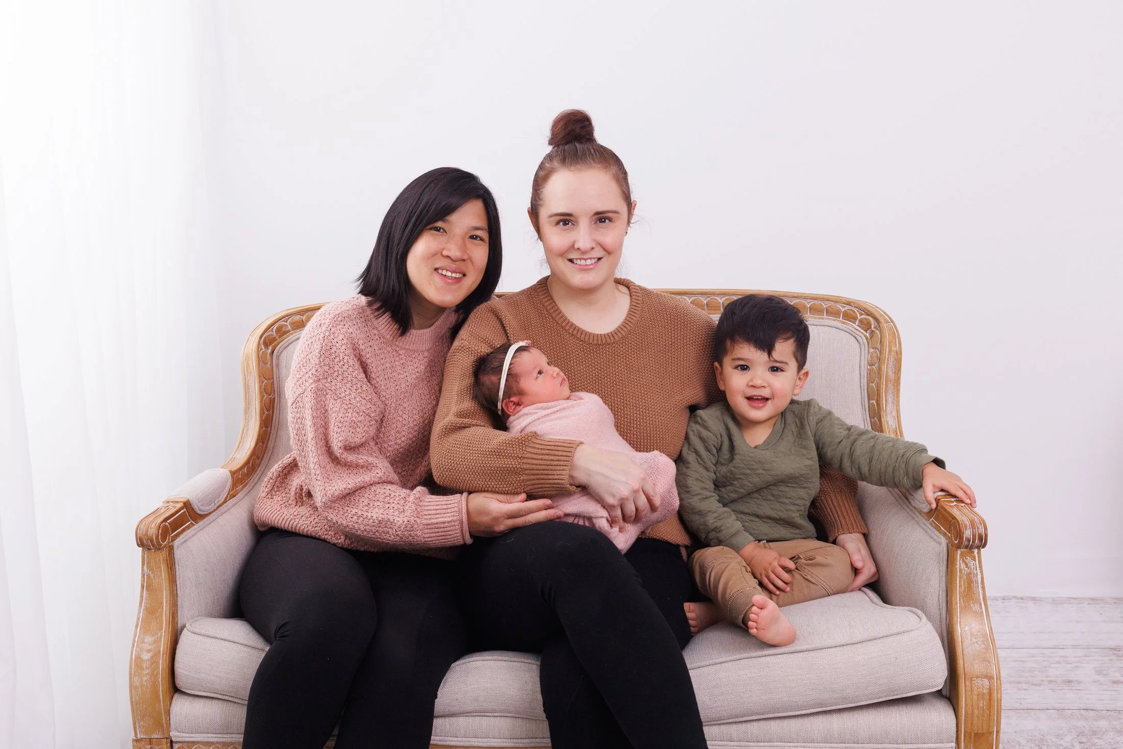 family of 4 with 2 moms, big brother and newborn sister on a couch