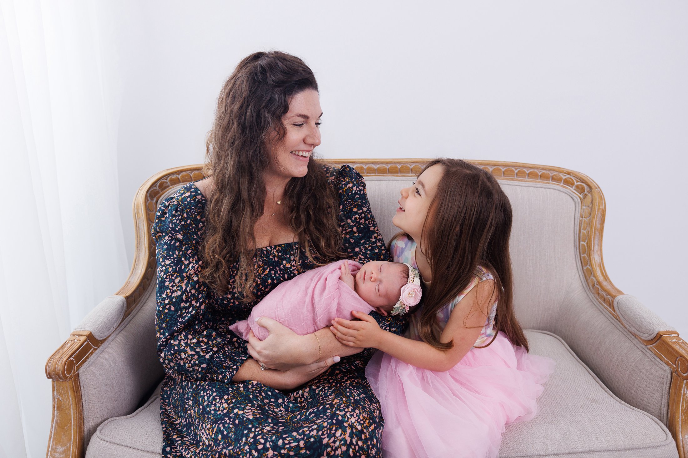mom wuth daughter and newborn baby on a couch