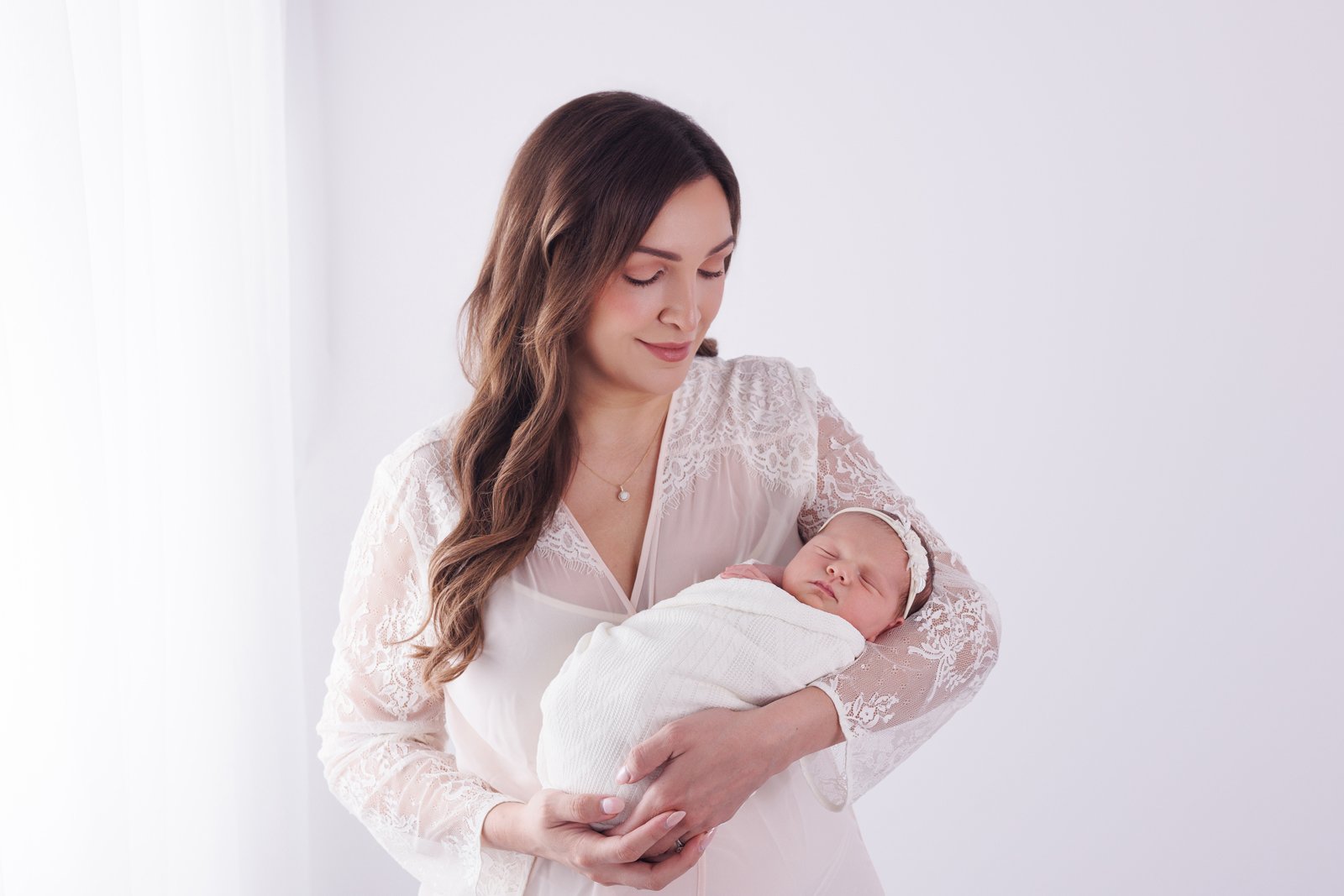 mom holding newborn baby dressed in white