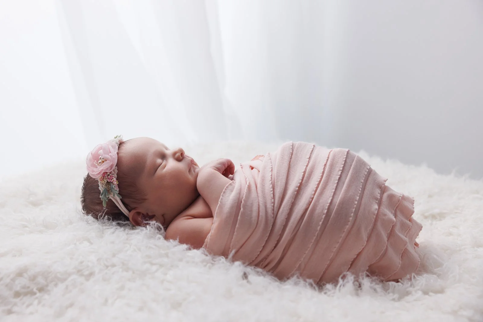 newborn baby on beanbag wrapped in pink